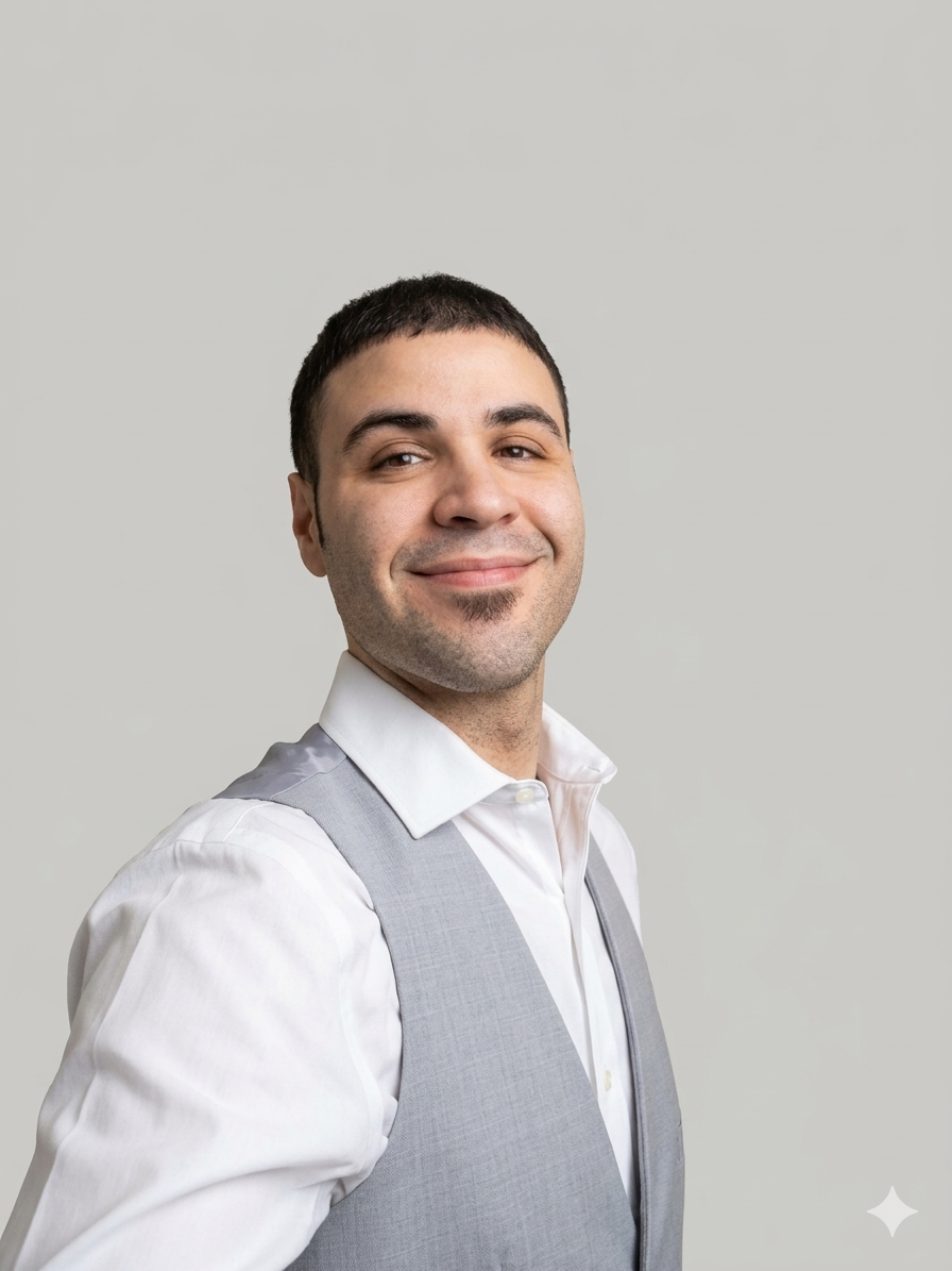 Marc Santiago in a white shirt and light gray vest smiling at the camera against a plain background.