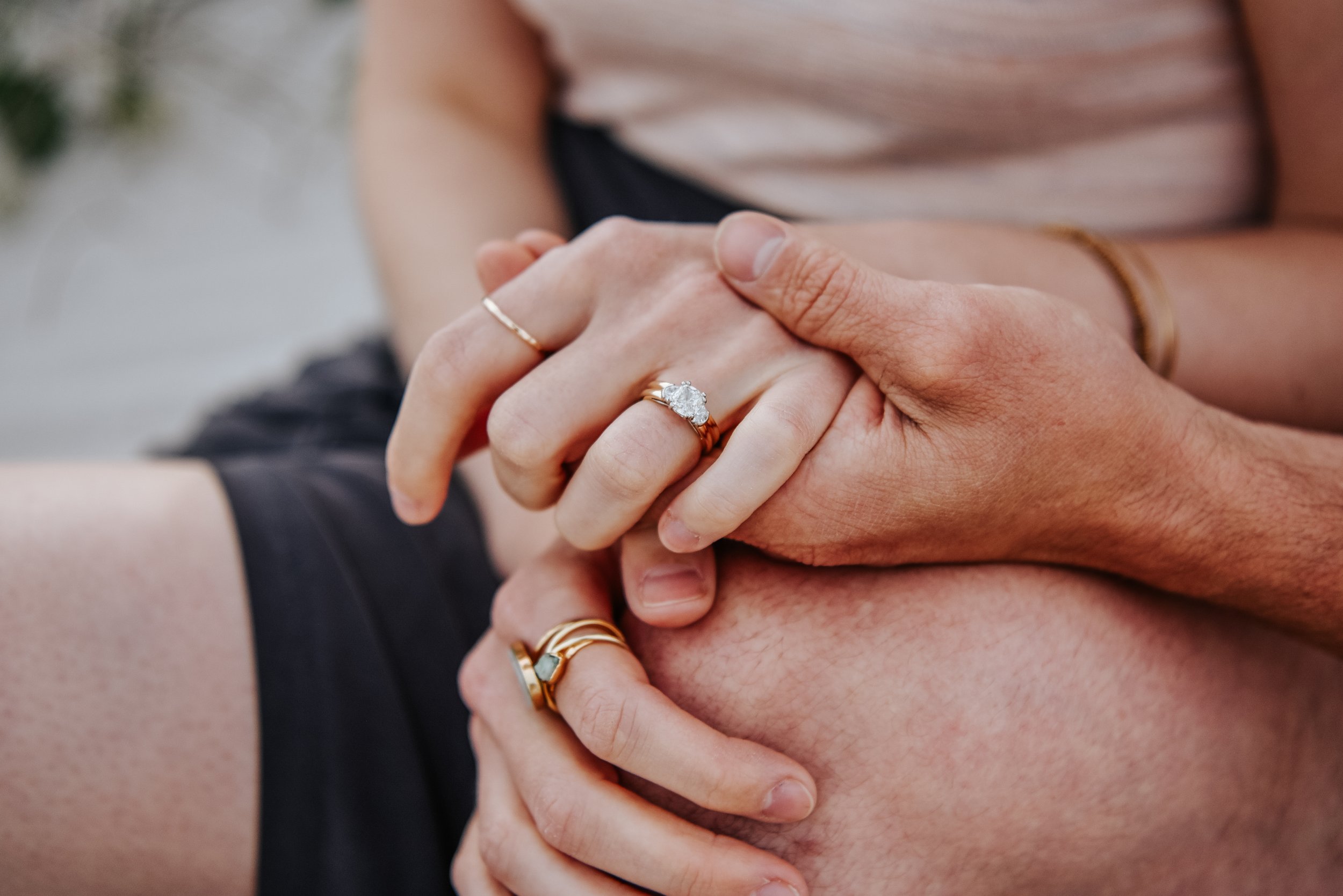 Close-up of a couple holding hands, displaying wedding and engagement rings.