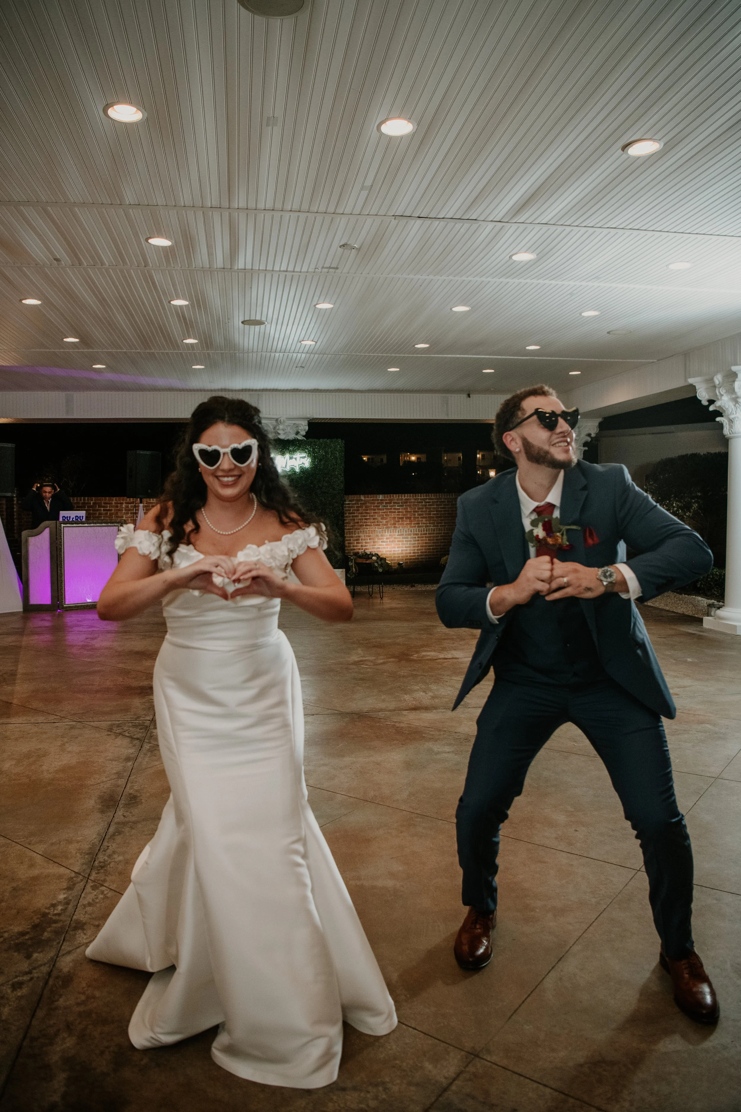 A bride and groom dancing at a wedding reception, wearing retro sunglasses and joyful expressions.