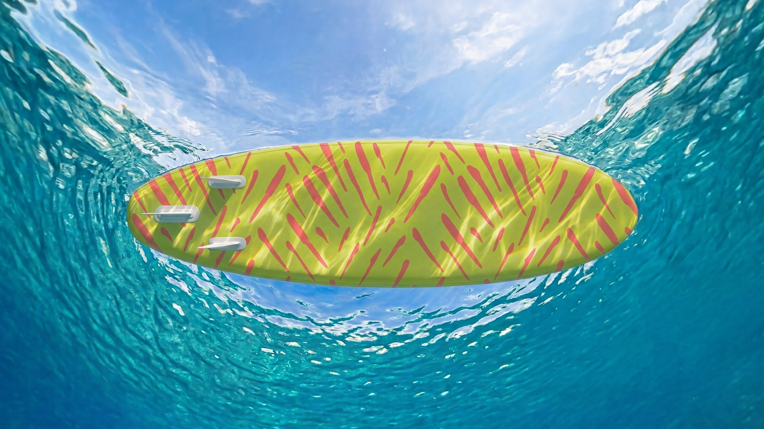 Underside of a paddleboard floating on a tropical ocean with a vibrant citrus green and pink pattern, seen from below the water