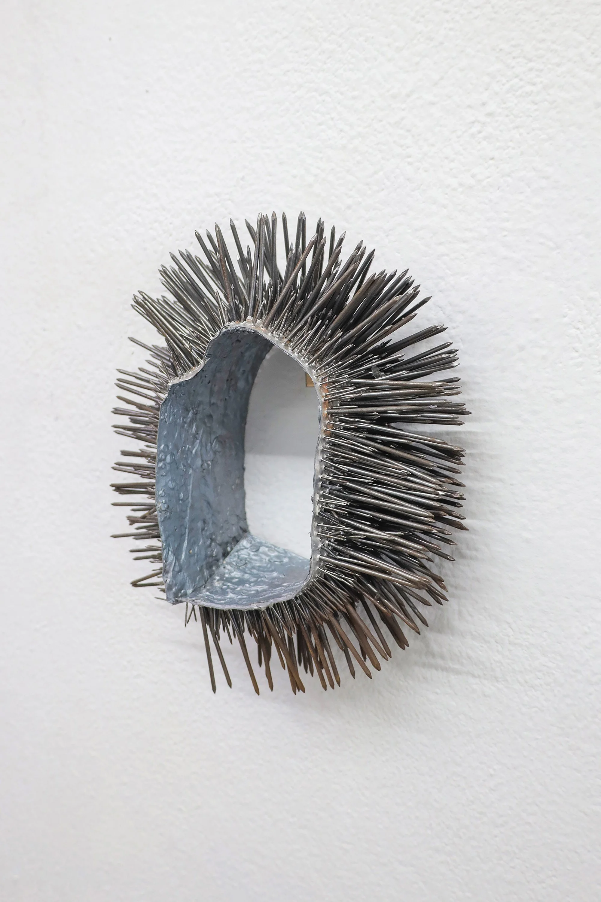  The wolf’s kiss, 2024 | Nails, aluminium, silicone, paint | 32x30x9cm | The wolf’s kiss unites danger and care within the same object. The nails, which were historically used to ward off wolf attacks, become ambiguous, simultaneously functioning as 