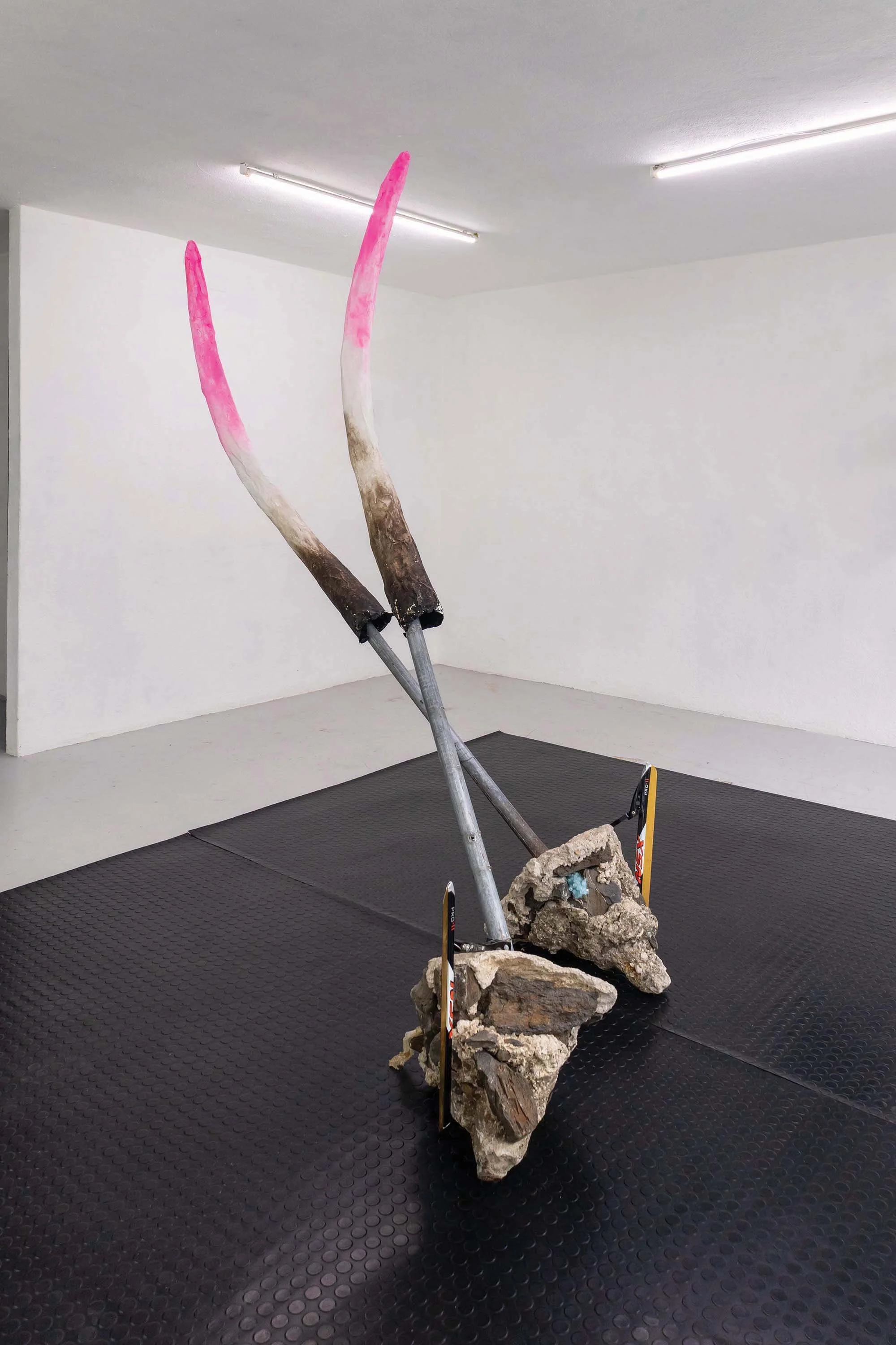 Two beasts, 2025 | Steel tube, cement, stone, paper, plaster, pigment, potassium alum crystals, snake ecdysis, speed ice skating blades, rubber flooring | 400x300cm | Two Beasts began with fragments torn from public spaces: remnants of street posts s
