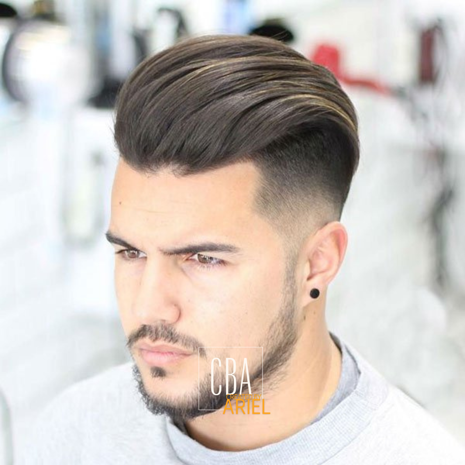 Close-up of a man's head showcasing a modern men's hairstyle with a fade cut and combed-back top, in a brightly lit salon or barbershop.