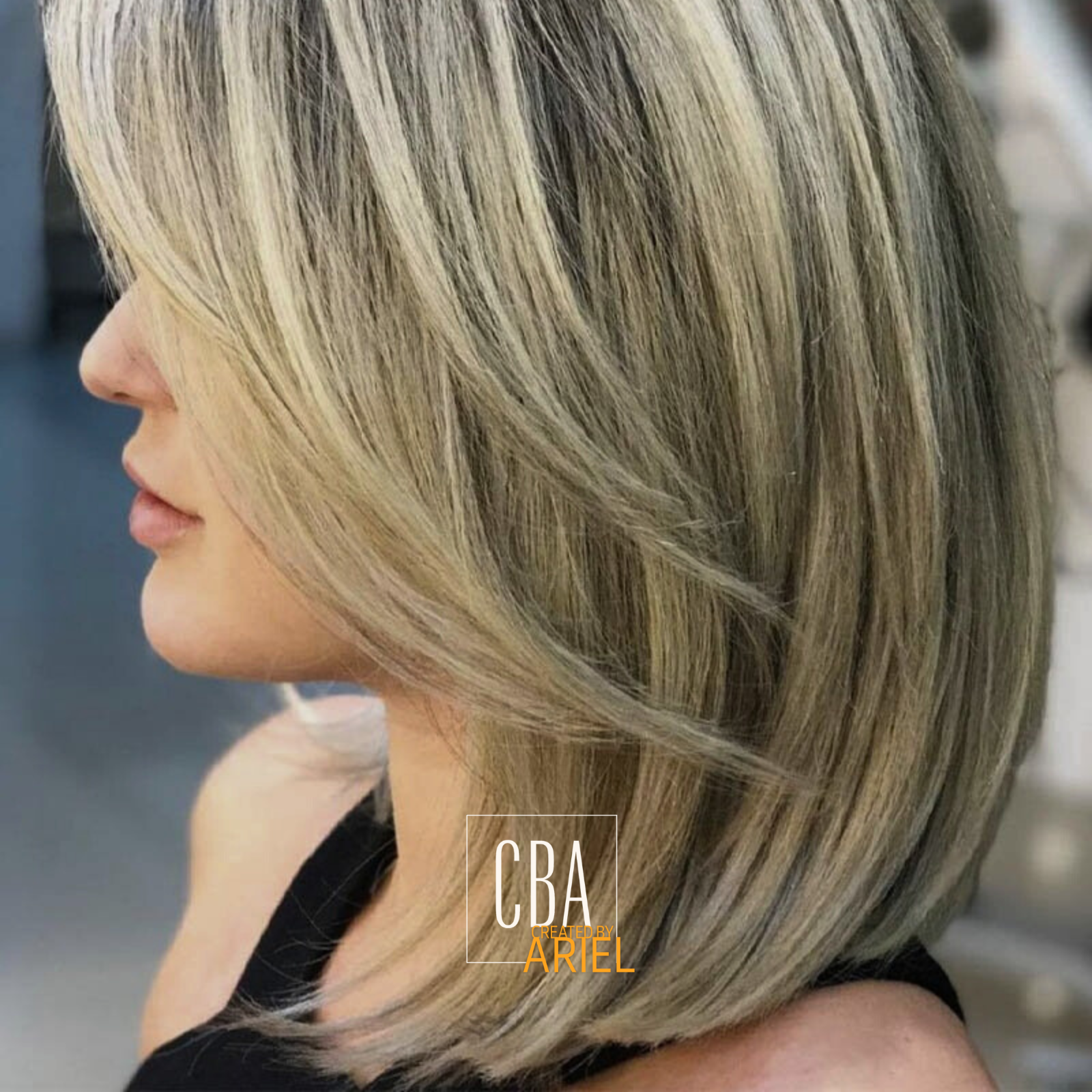 Side view of a woman with shoulder-length blonde hair with highlights, wearing a black top.