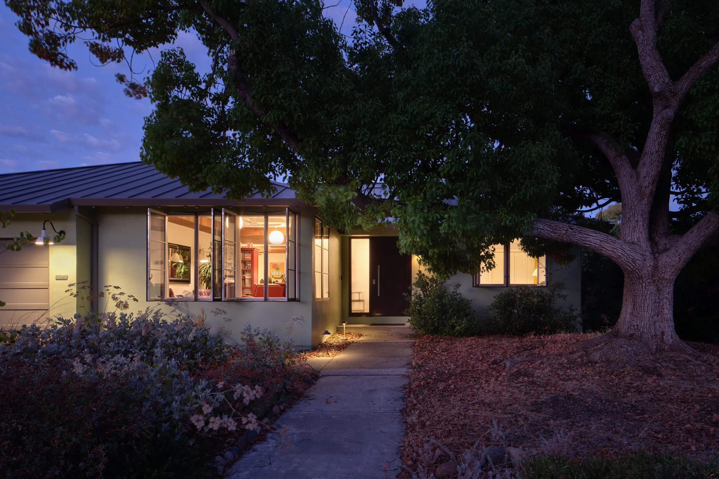 Twilight view of exterior with standing seam roof and illuminated interior