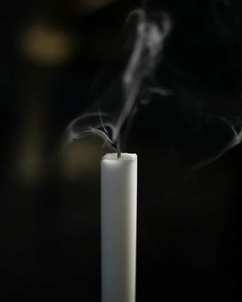 A white candle with smoke coming out of it
