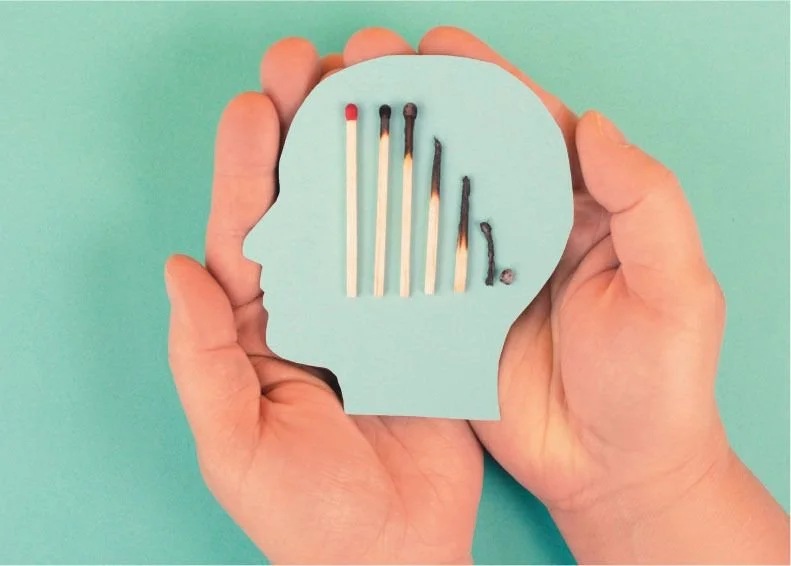 A hand holding a blue cardboard head with matches in the shape of a head