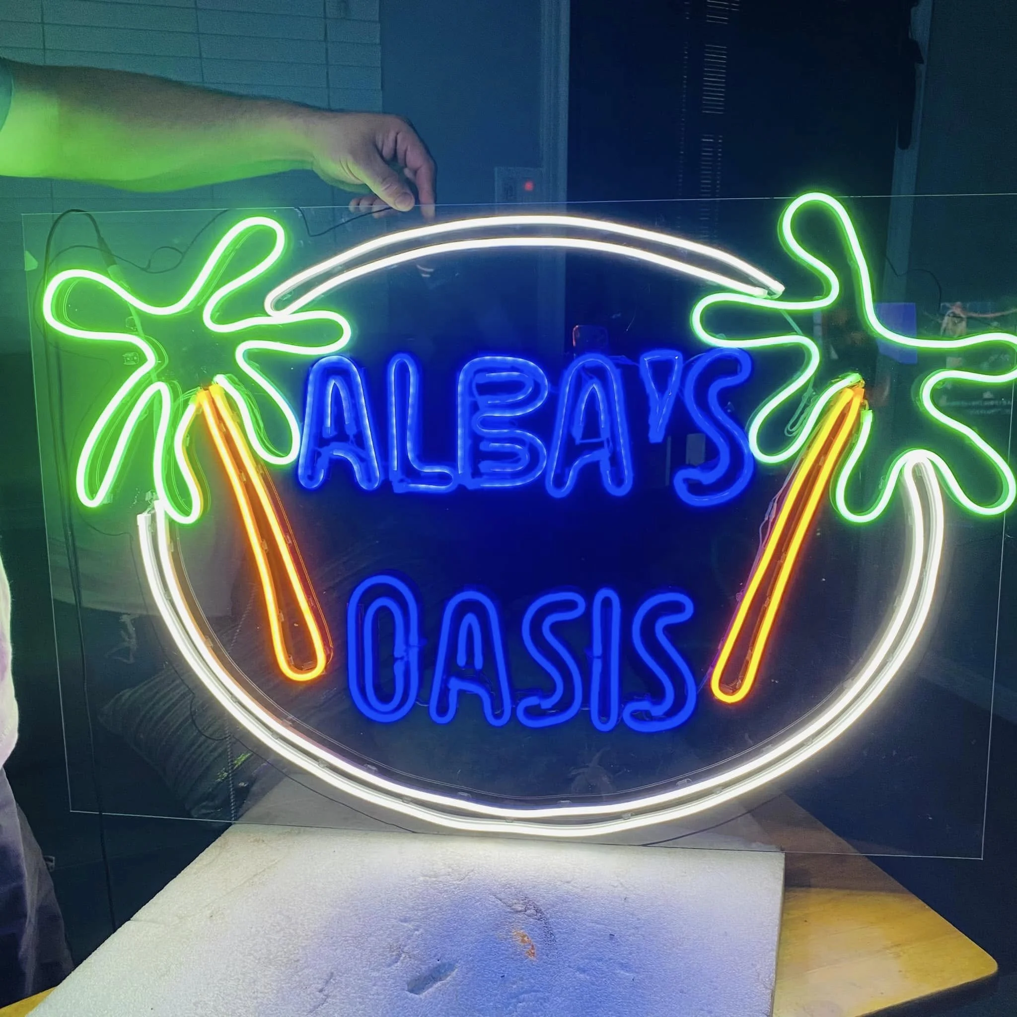 Colorful neon sign with green, white, yellow, and blue lights, forming digital patterns and the word 'Open' at the bottom.