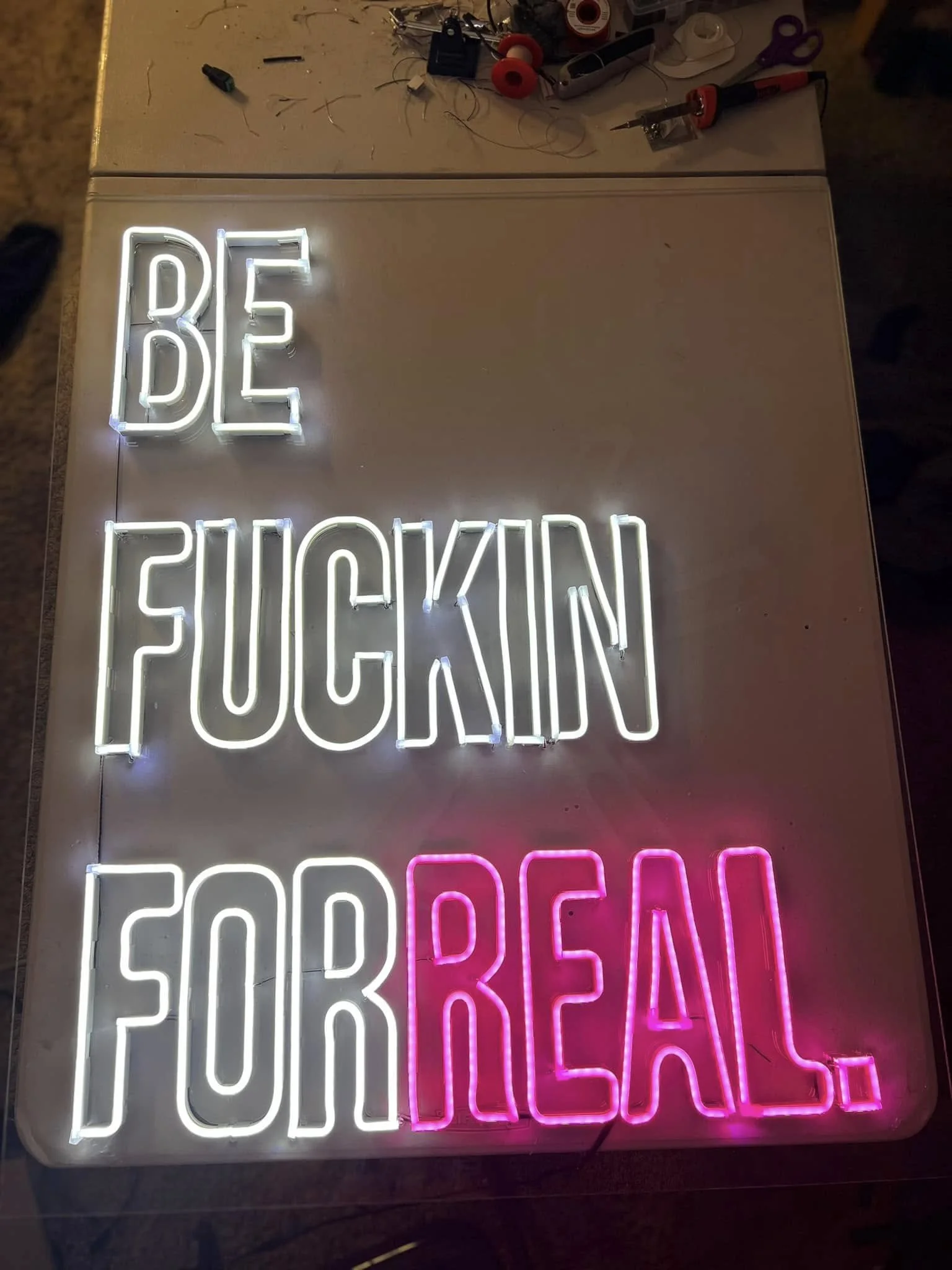 Colorful neon sign with the words 'BE QUICK' in white, 'FOOD' in pink, and another word partially visible beneath.