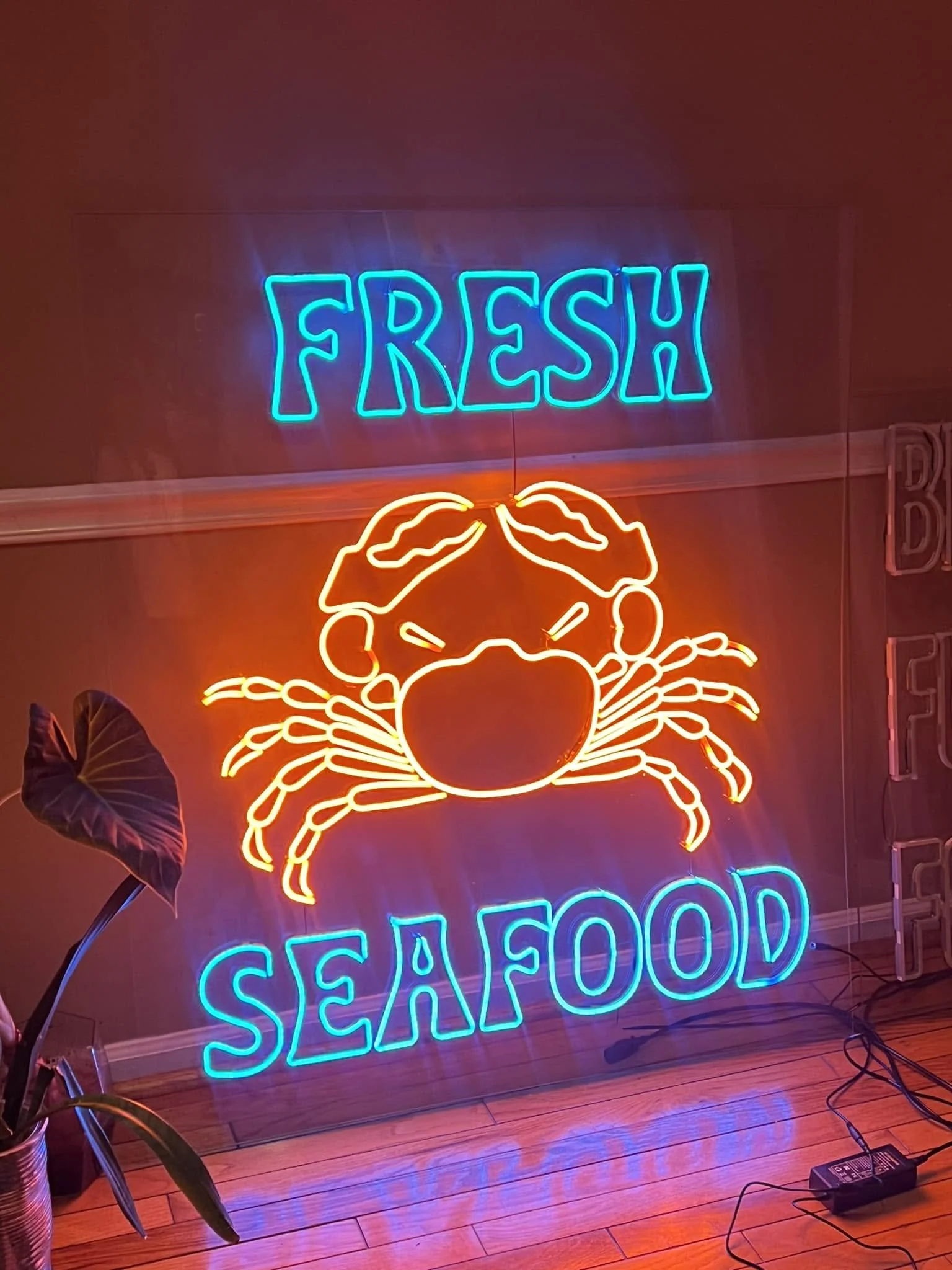 Neon sign displaying the words 'FRESH' in blue, a red neon crab, and the word 'SEAFOOD' in blue on a wall.