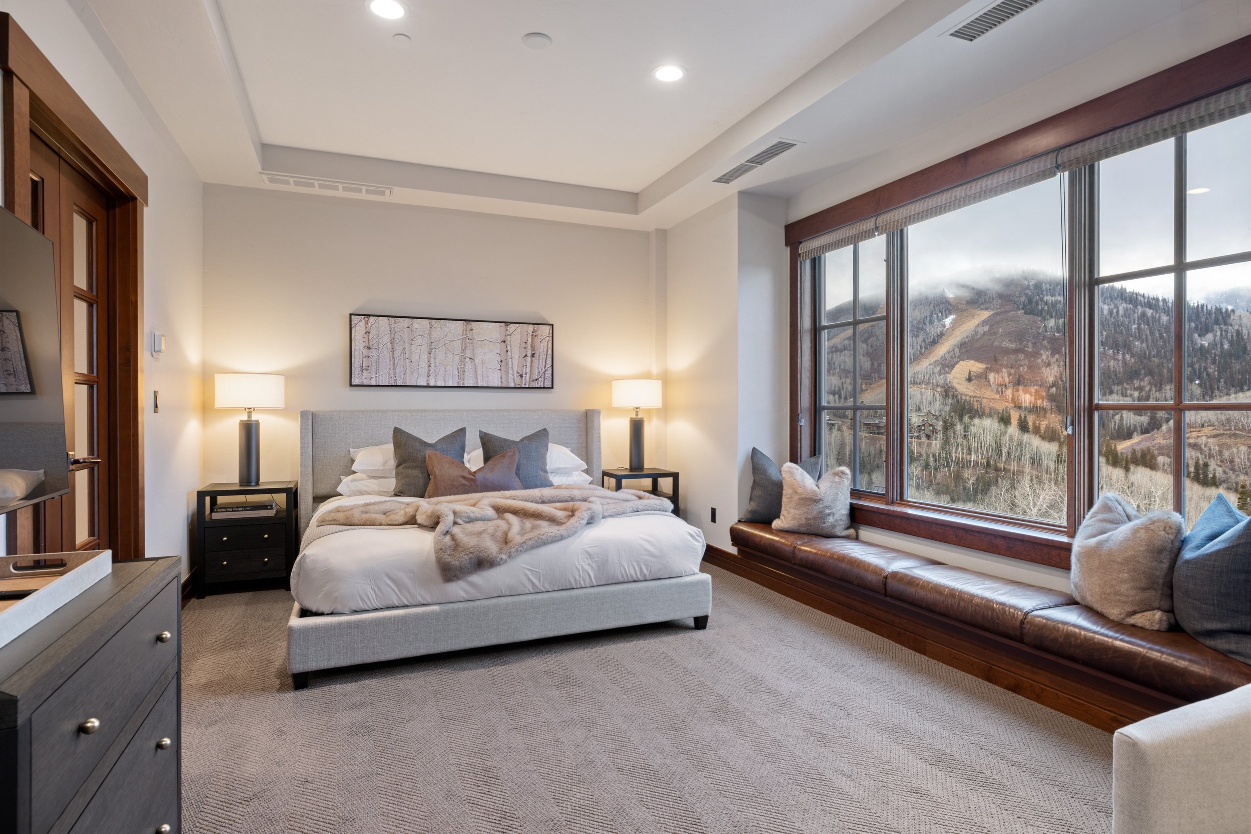 Primary suite with king bed, fur throw, and sweeping mountain views