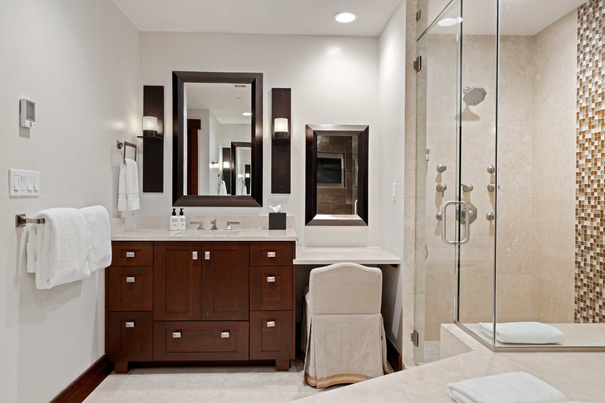 Primary bath vanity with seated dressing area and glass-enclosed shower