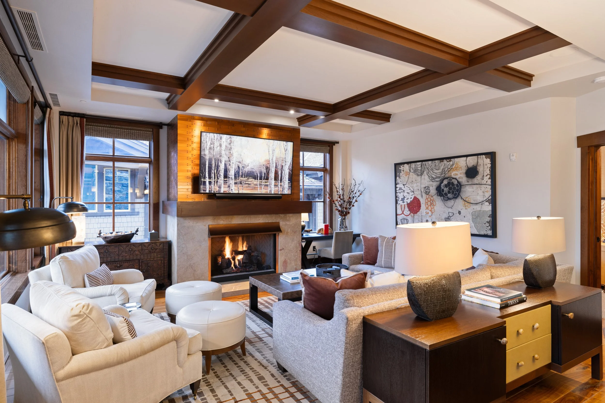 Spacious living room with coffered ceilings, gas fireplace, and curated artwork