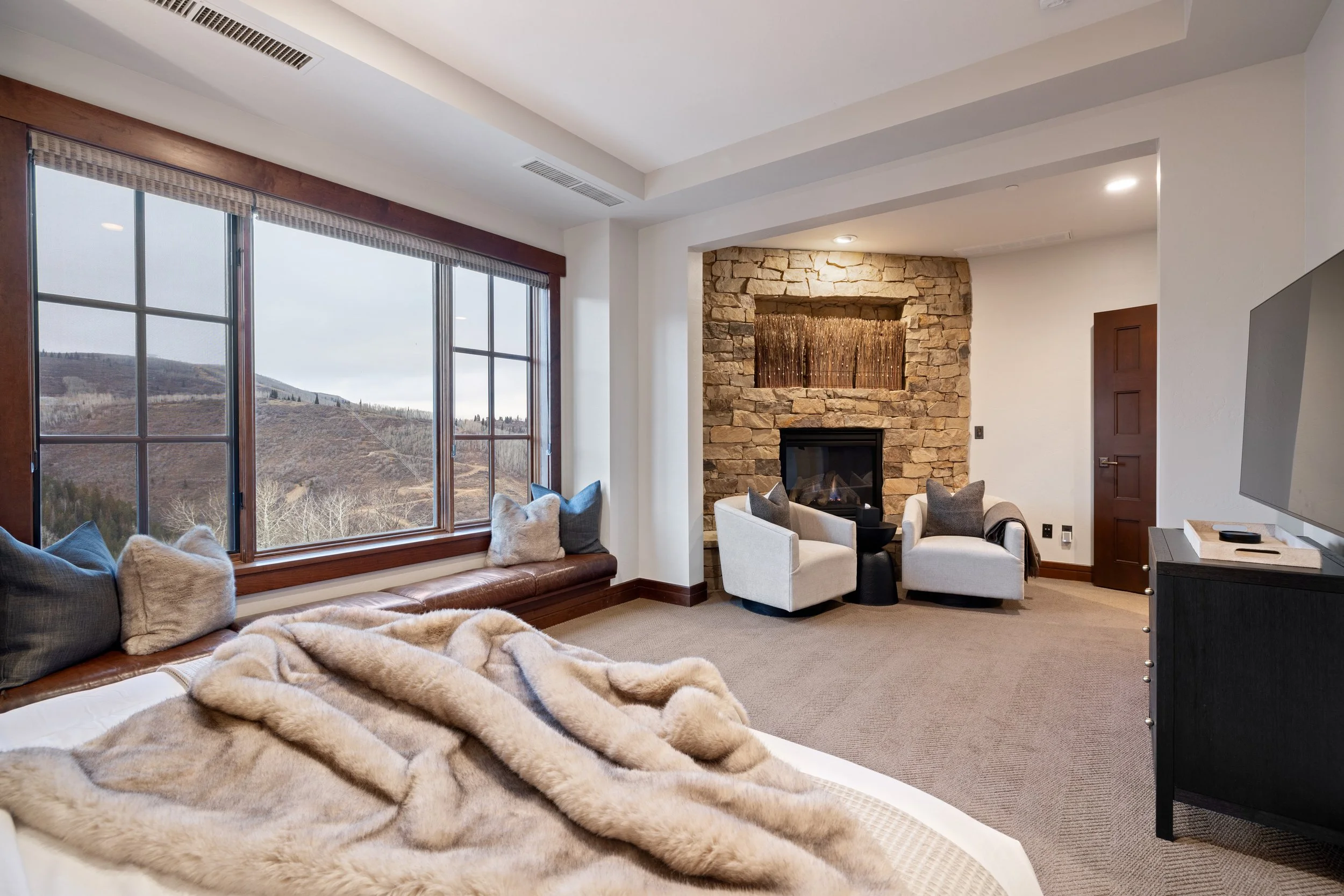 Primary suite sitting area with stone fireplace, TV, and panoramic views
