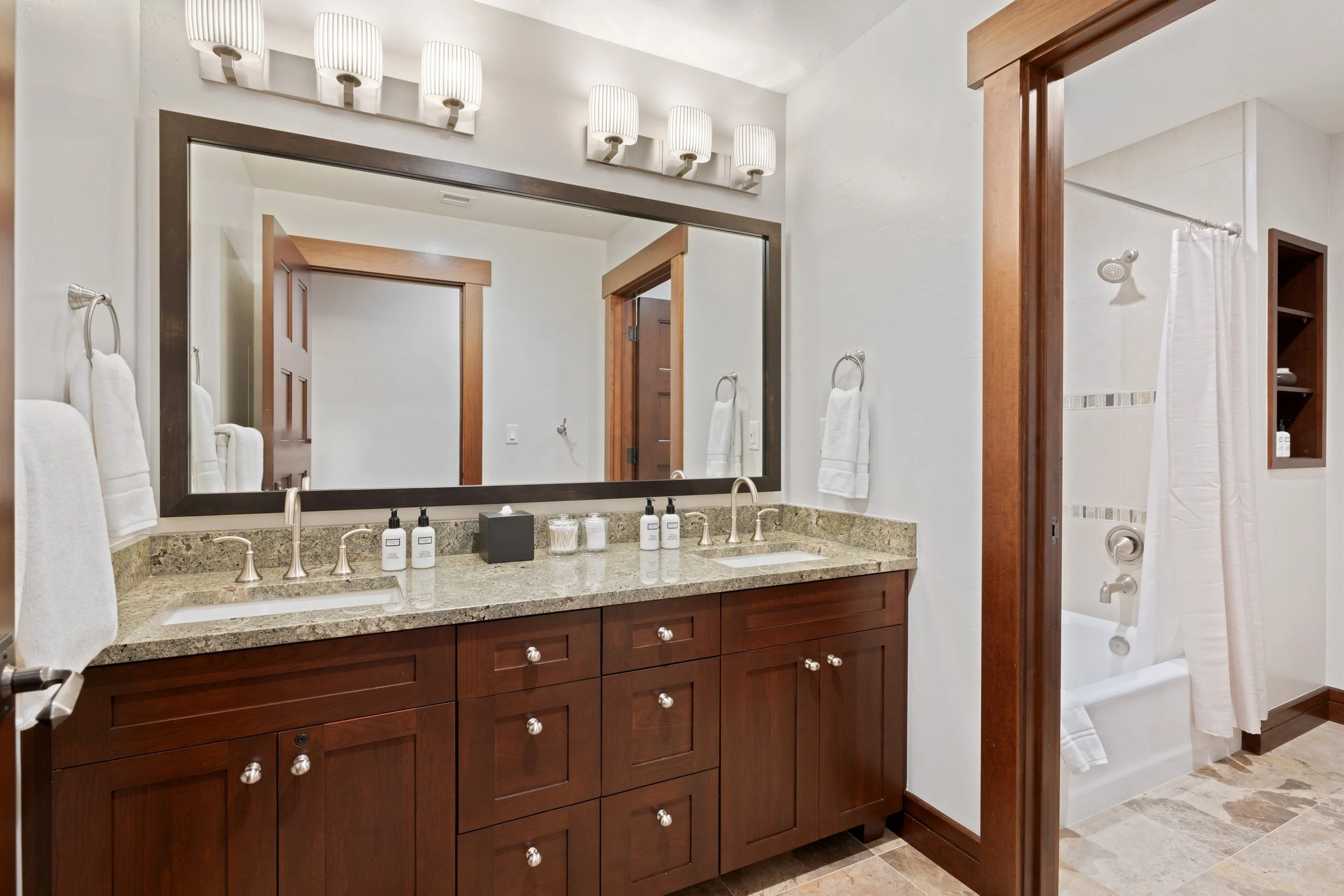 Bunk room bath with double vanity, tub/shower combination, and full amenities