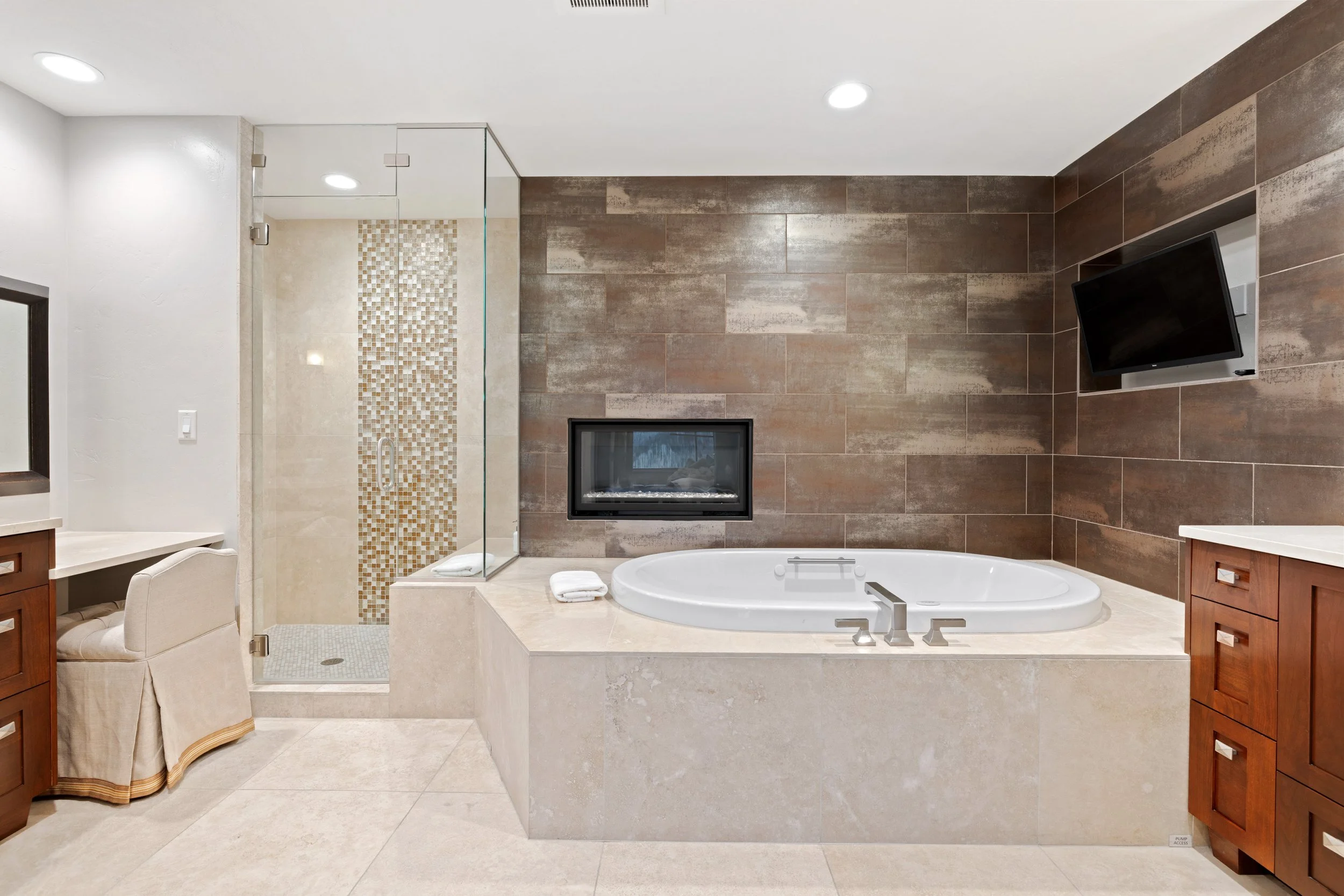Primary bath with jetted soaking tub, glass shower, fireplace, heated floors, and TV