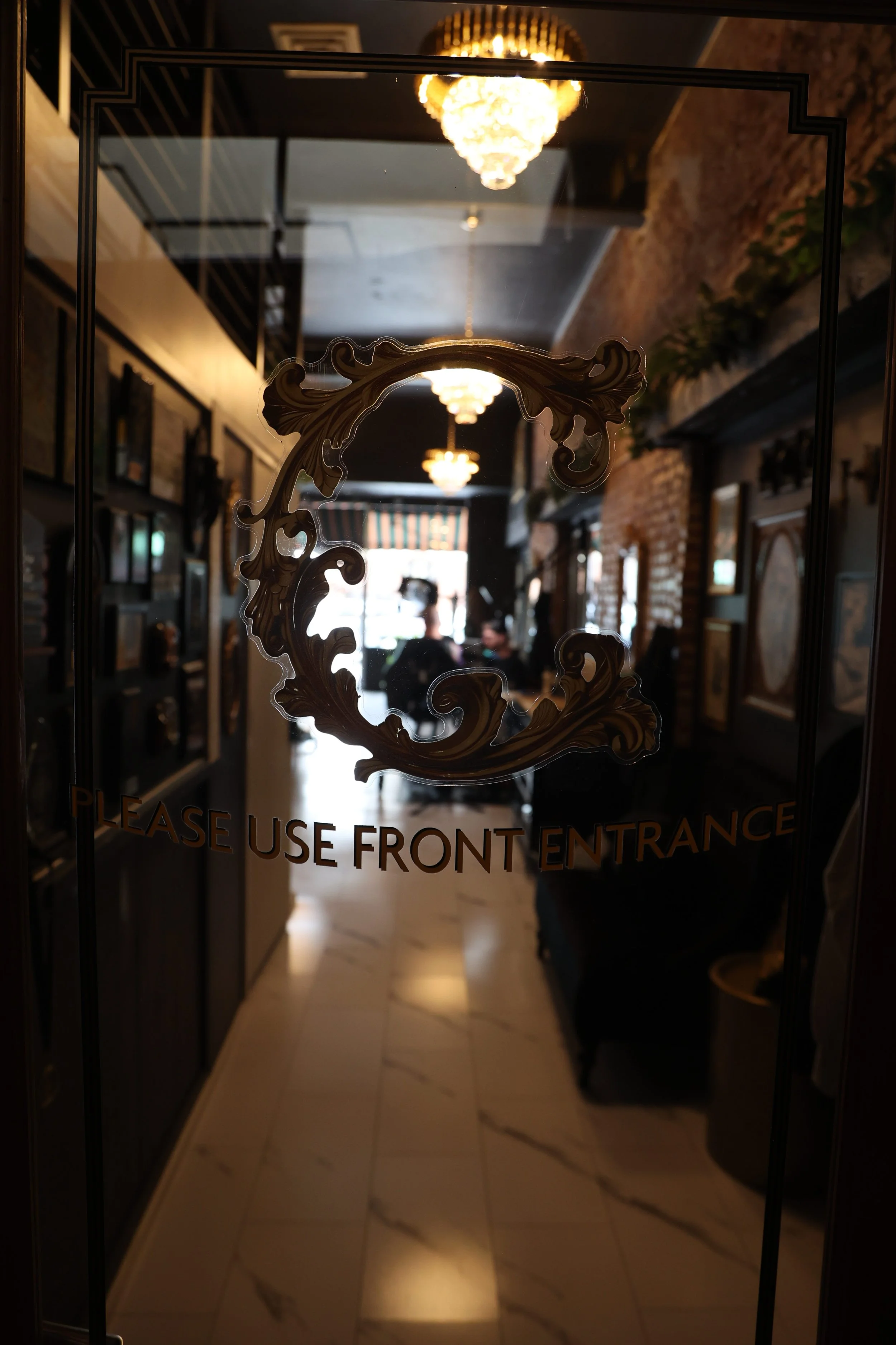 A glass door secret entrance features the Chariot logo and peaks into the award and trophy wall as clients are getting tattoo sessions from their award winning tattoo artist. 