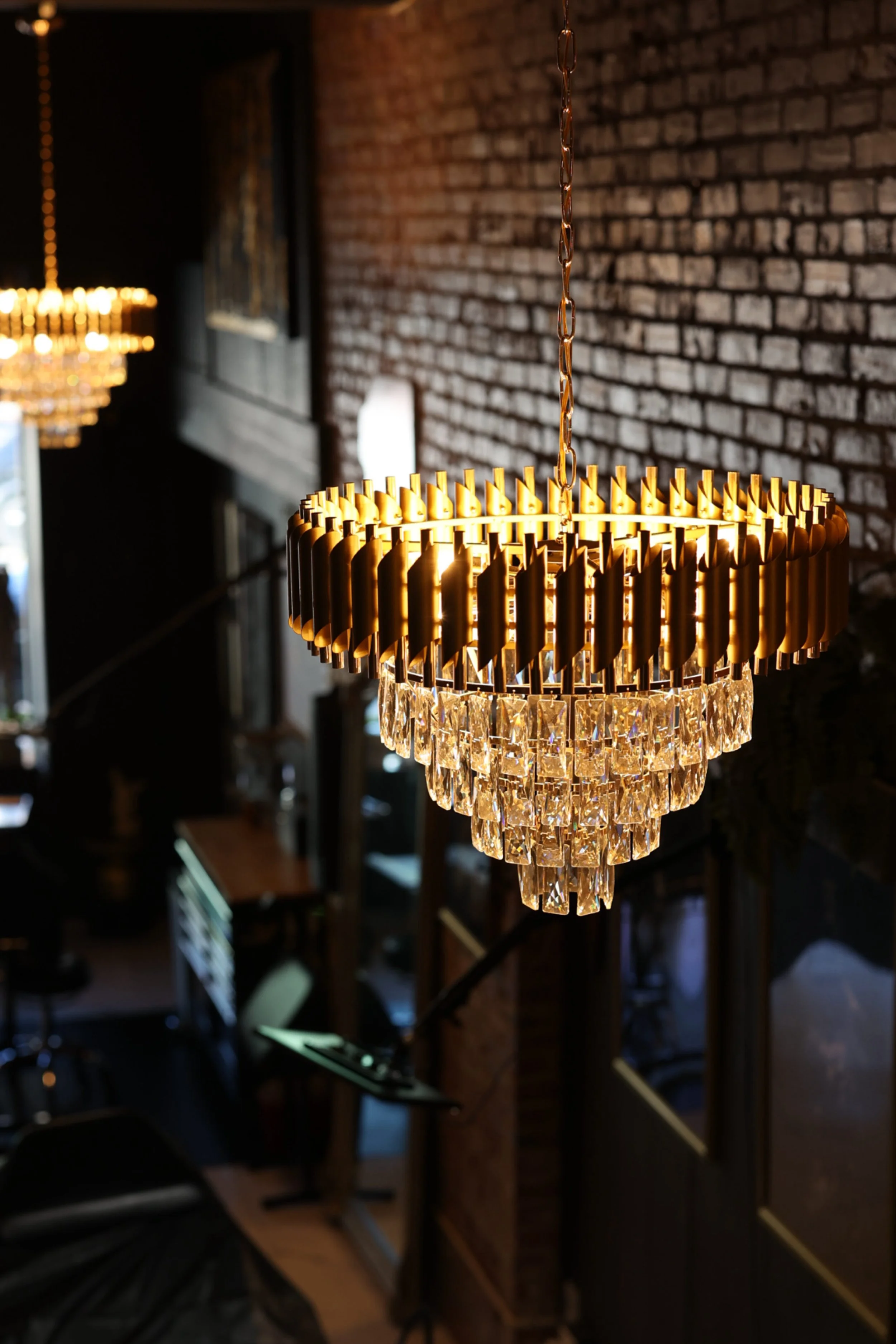 Unique gold crystal chandeliers suspend from the ceiling and reflect upon the large framed art and mirrors around this elegant Boise tattoo studio. 