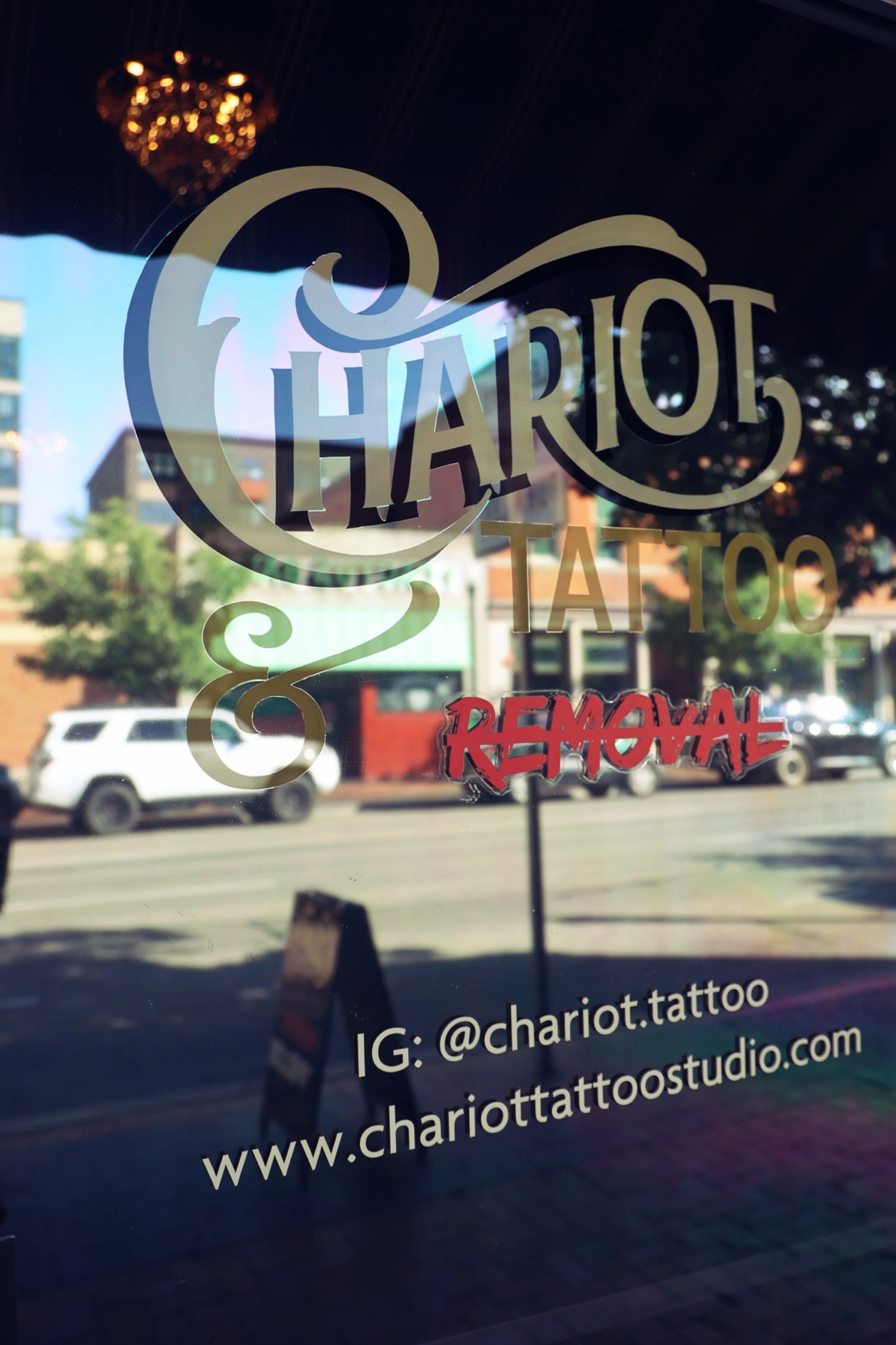 Hand-painted door sign on main street Boise front door advertising Chariot Tattoo and Laser Tattoo Removal with contact information and an inviting peak as to the superiority of art and services that reside inside. 