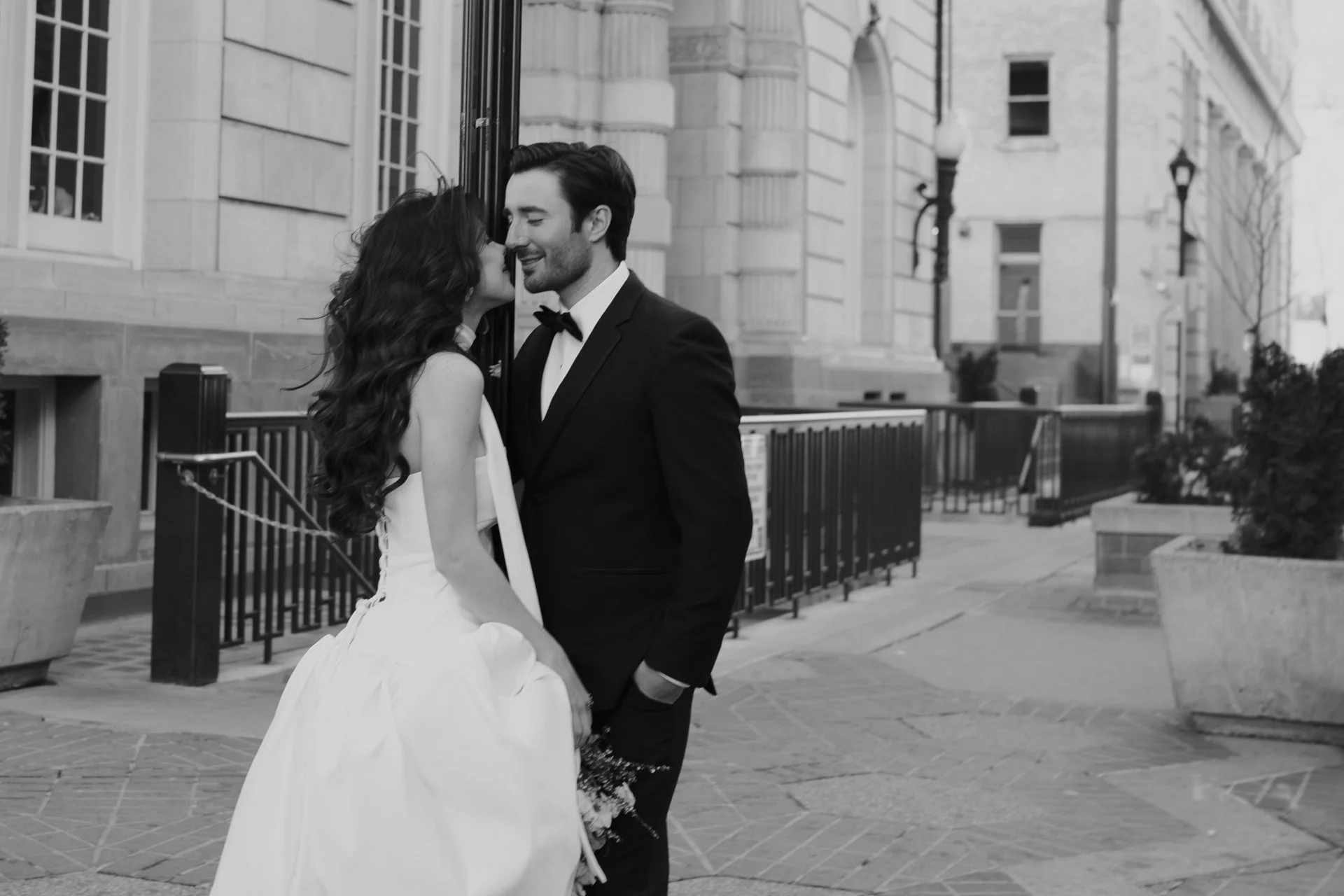 Bride and Groom in classic elegant wedding attire surrounded by beautiful stonework architecture during a downtown formals photoshoot - Poise and Ivy Imagery