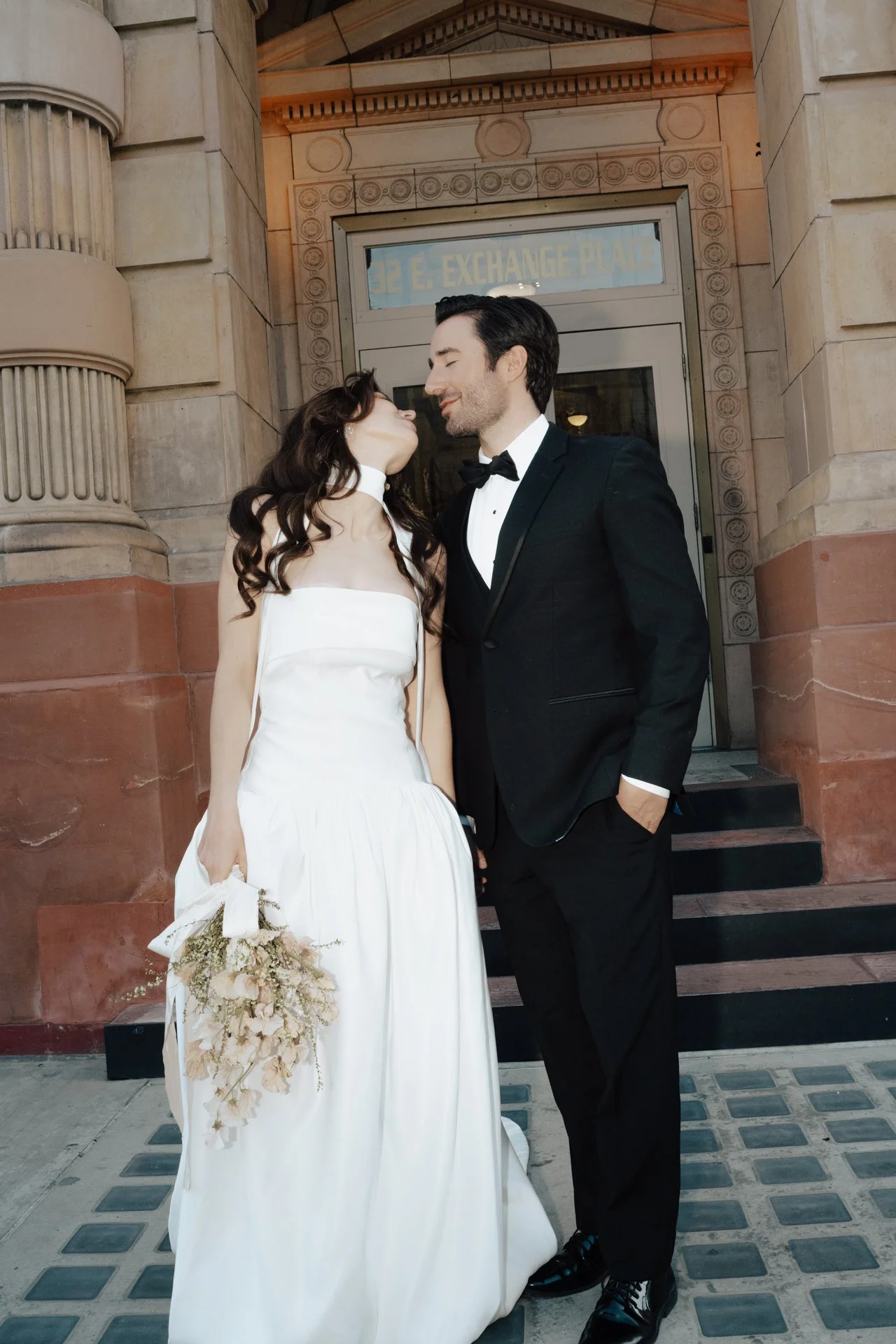 Bride and Groom in classic elegant wedding attire surrounded by beautiful stonework architecture during a downtown formals photoshoot - Poise and Ivy Imagery