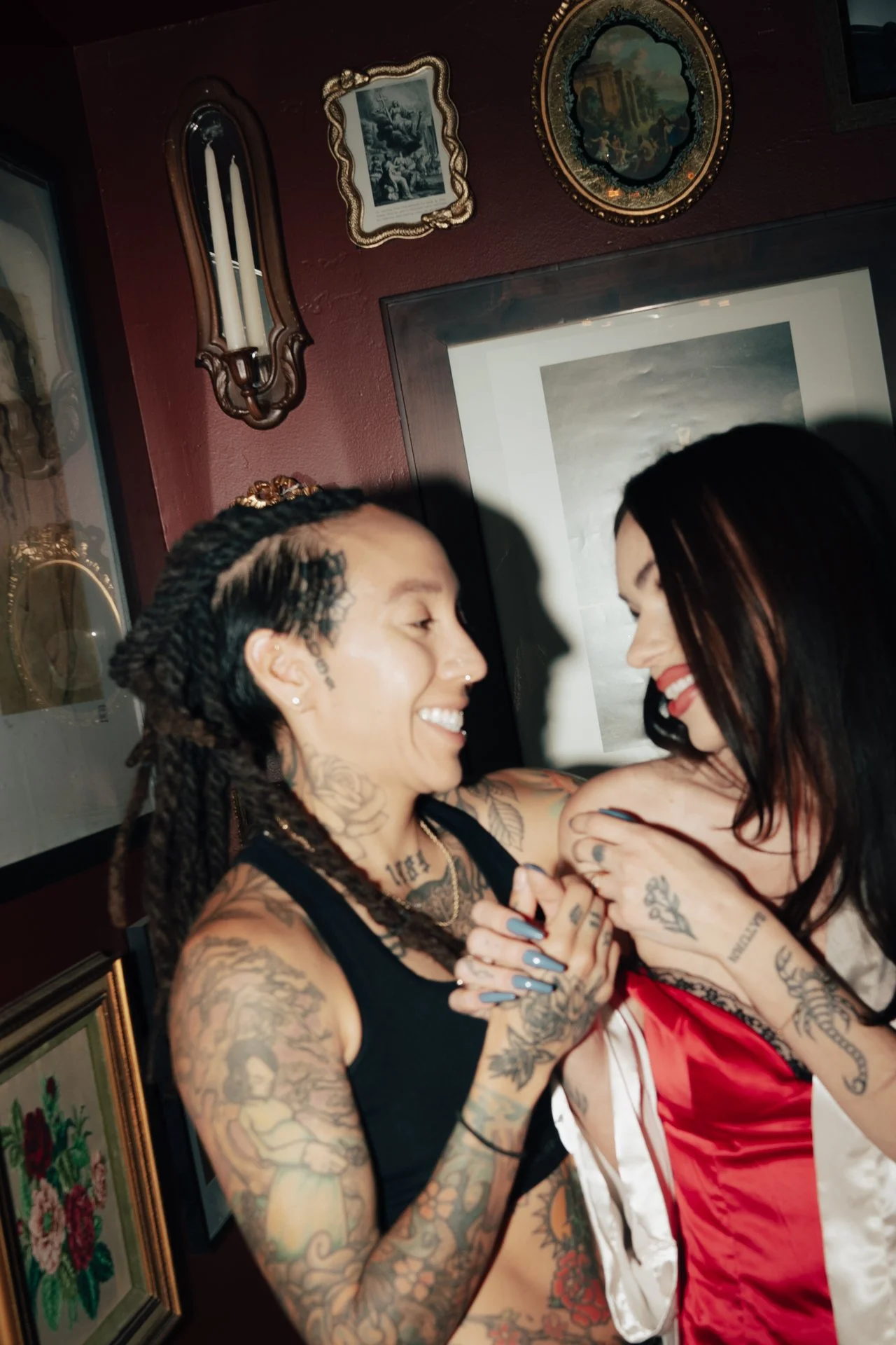 a tattooed couple embrace each other in front of ornate artworks - photographed by Poise and Ivy Imagery