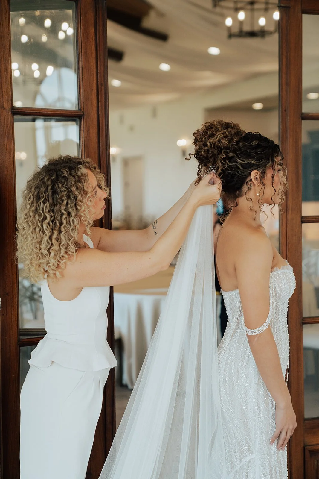 Bride getting her veil placed by her hair artist before her wedding ceremony - photography by Poise and Ivy Imagery