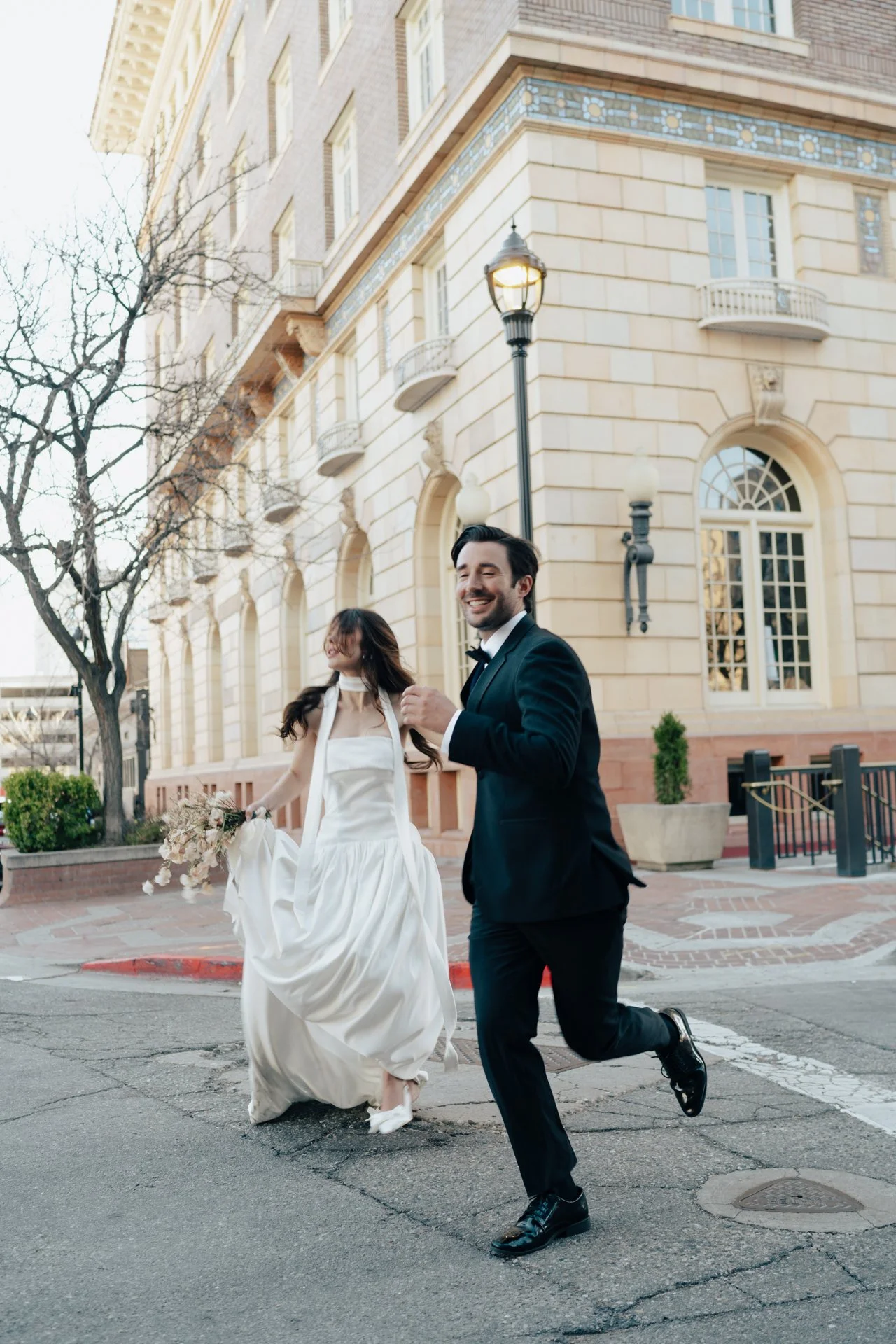 Bride and Groom in classic elegant wedding attire surrounded by beautiful stonework architecture during a downtown formals photoshoot - Poise and Ivy Imagery