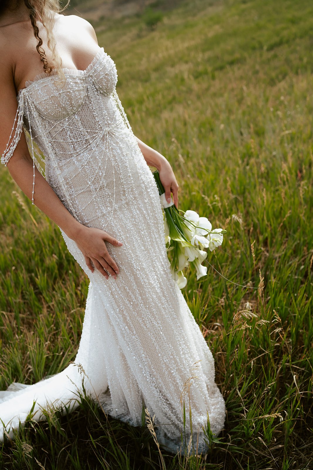 a bride wearing a beaded wedding gown in a sunlit meadow. Photography by Poise and Ivy Imagery