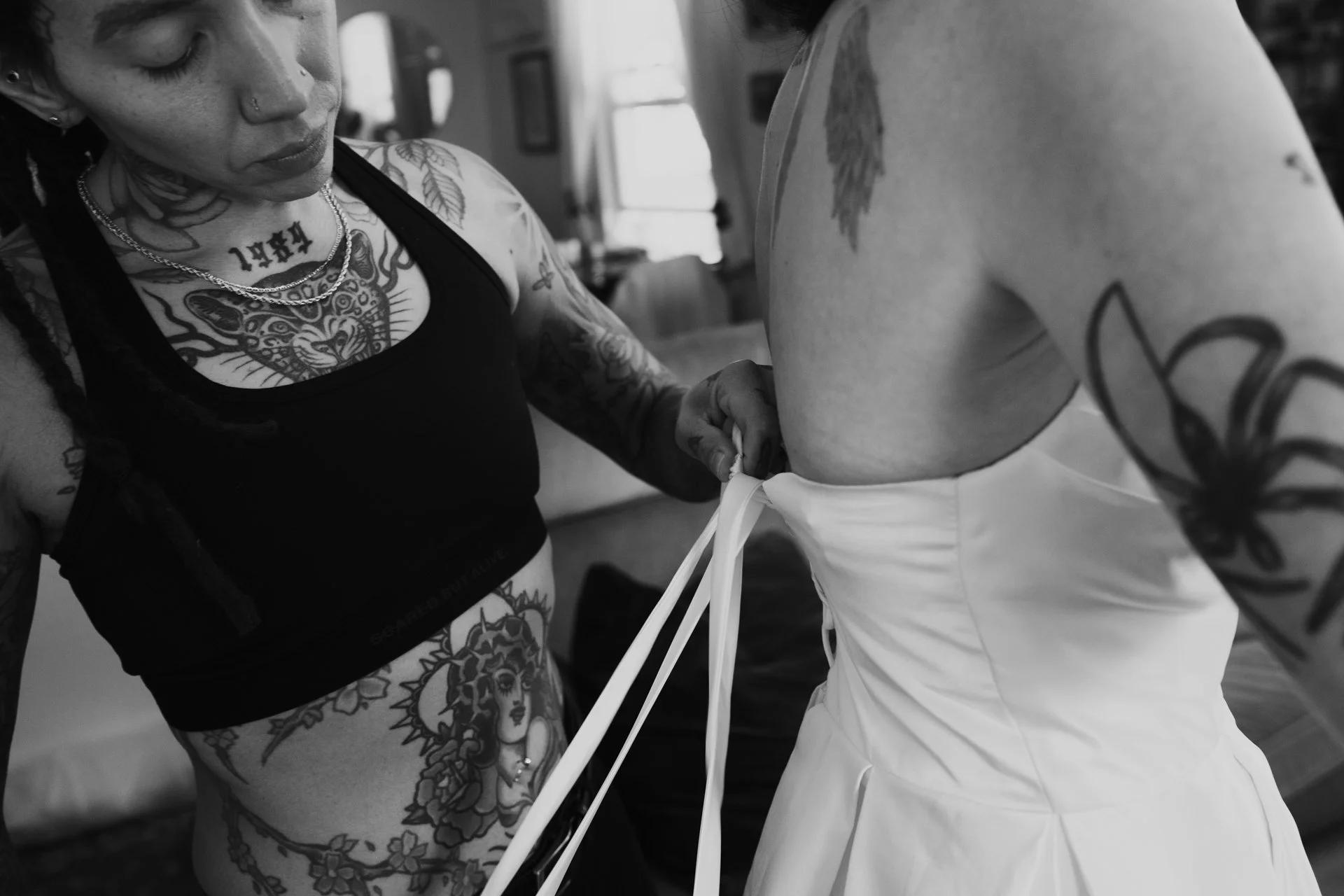 a tattooed couple embrace each other as they dress in their wedding attire - photographed by Poise and Ivy Imagery