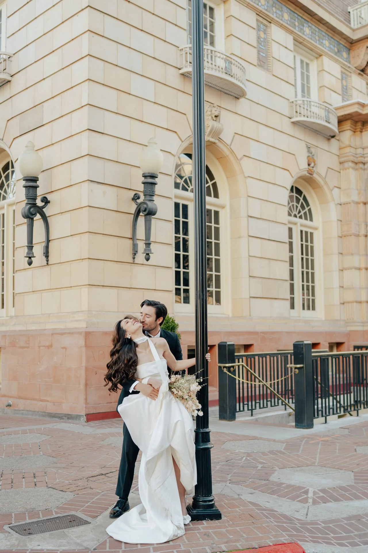 Bride and Groom in classic elegant wedding attire surrounded by beautiful stonework architecture during a downtown formals photoshoot - Poise and Ivy Imagery