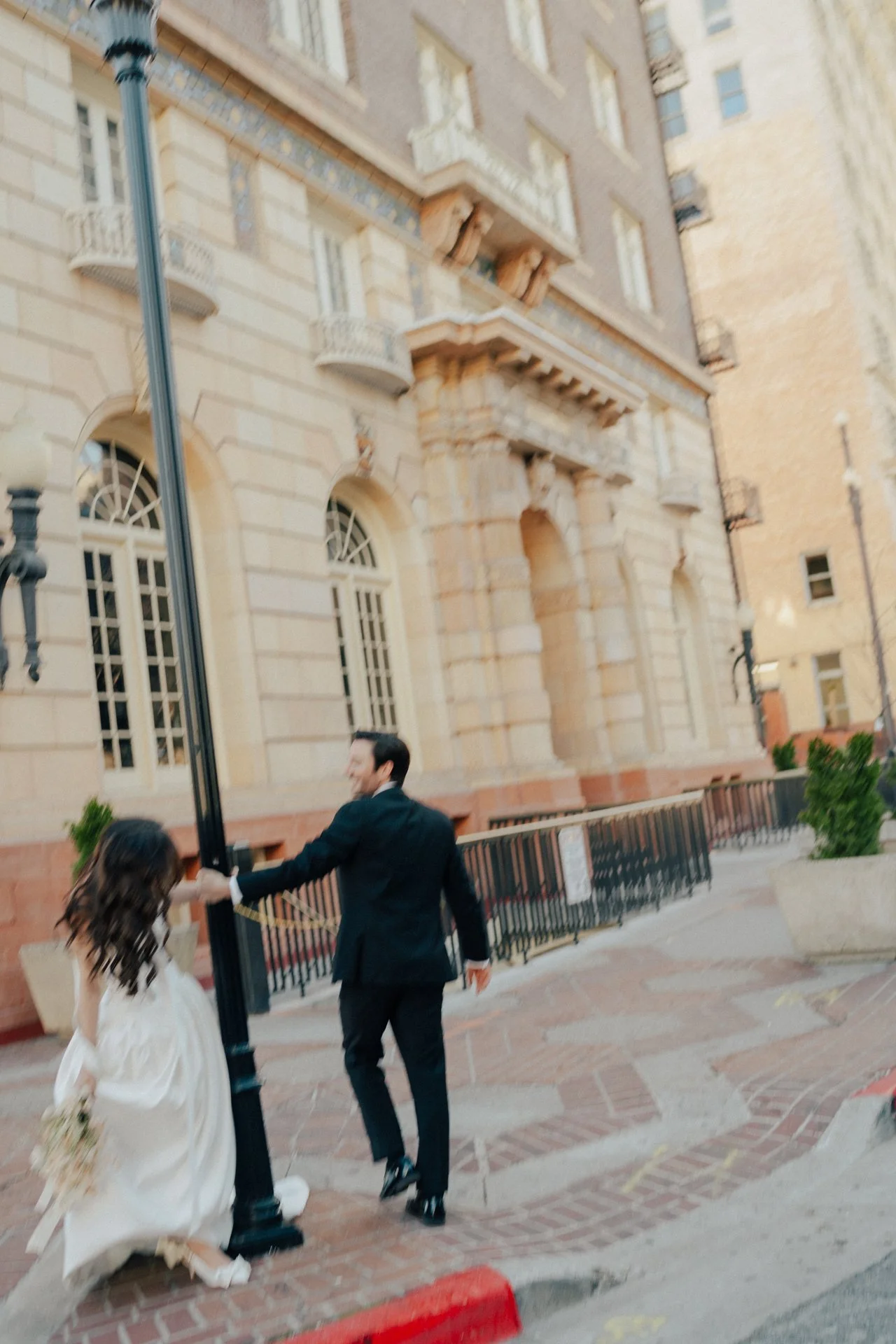 Bride and Groom in classic elegant wedding attire surrounded by beautiful stonework architecture during a downtown formals photoshoot - Poise and Ivy Imagery