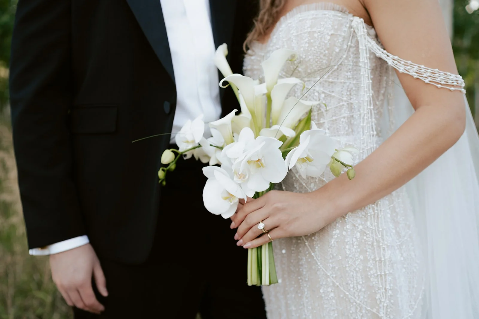 a bride and a groom stand together in a lush aspen grove. the bride wears a beaded wedding gown with a bridal veil and the groom wears a tuxedo. Photography by Poise and Ivy Imagery