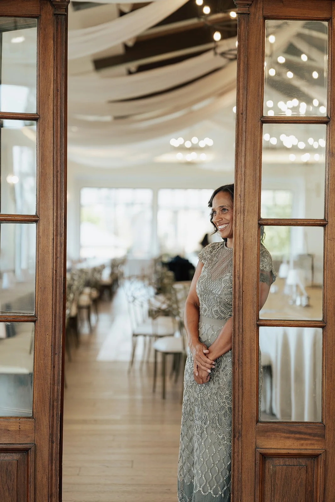 woman looks through an ornate doorway to wittness her daughter preparing for her wedding off screen- poise and ivy imagery