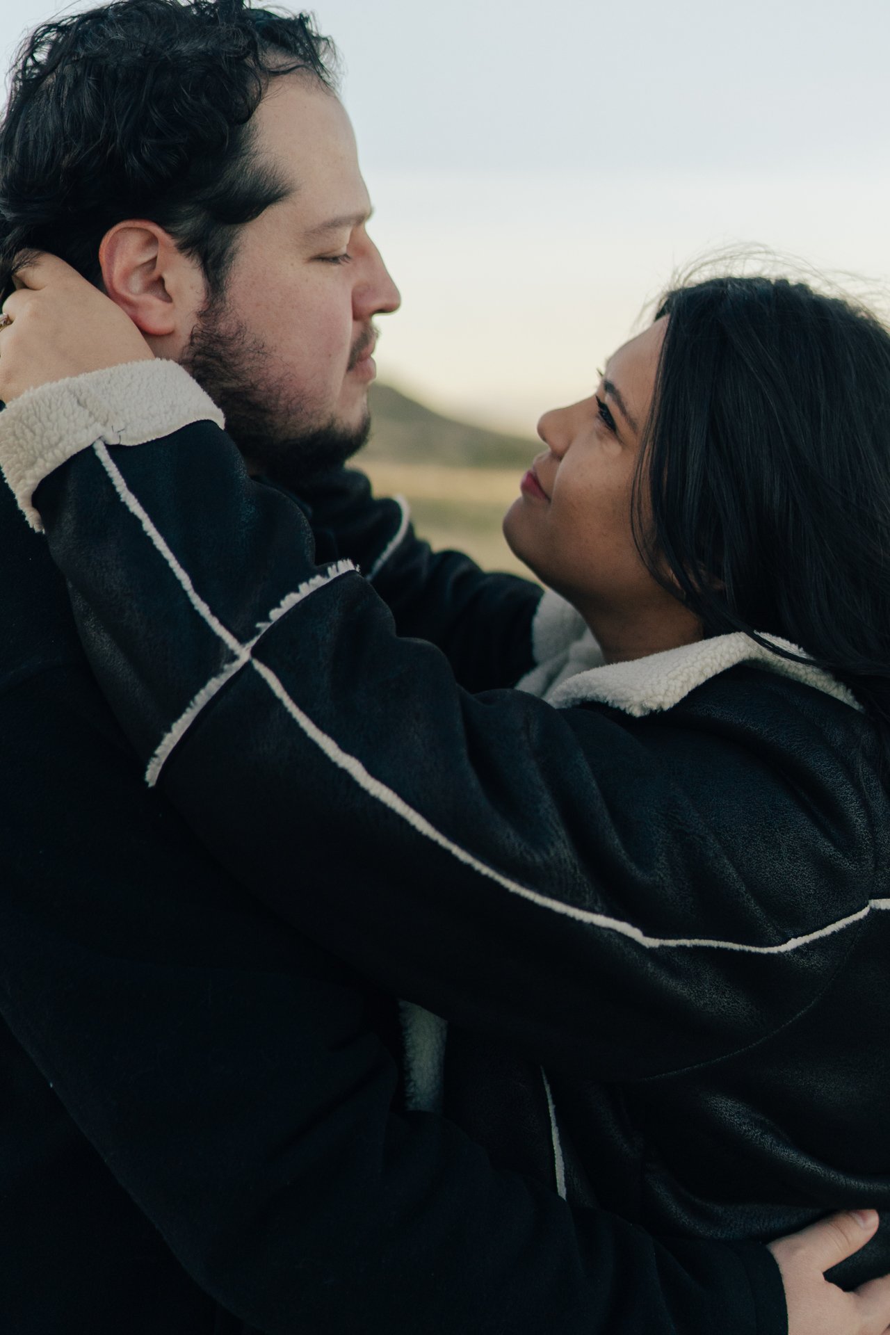 a couple stands together in a softly lit green field together - photographed by poise and ivy imagery
