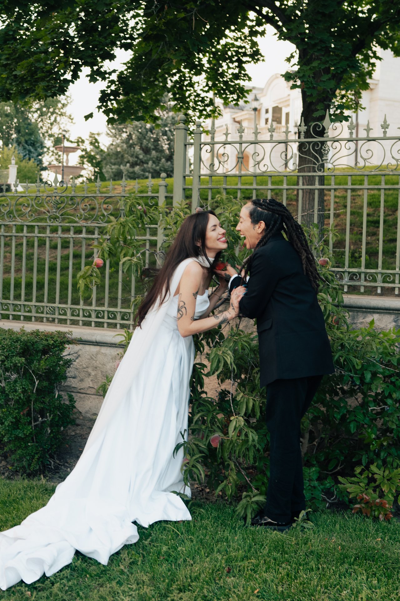Two brides embrace in front of an ornamental museum of art - poise and ivy imagery