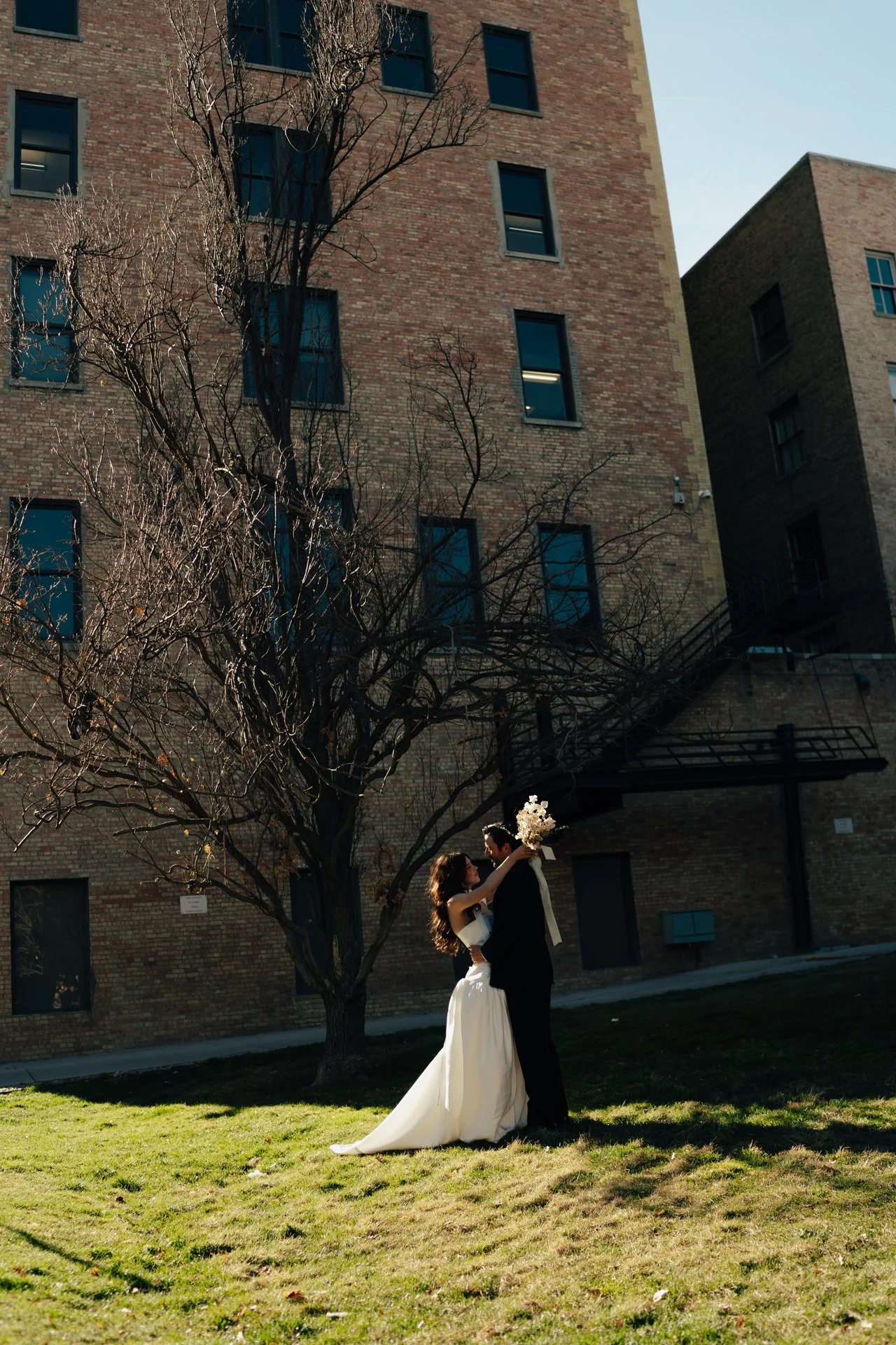 Bride and Groom in classic elegant wedding attire surrounded by beautiful stonework architecture during a downtown formals photoshoot - Poise and Ivy Imagery