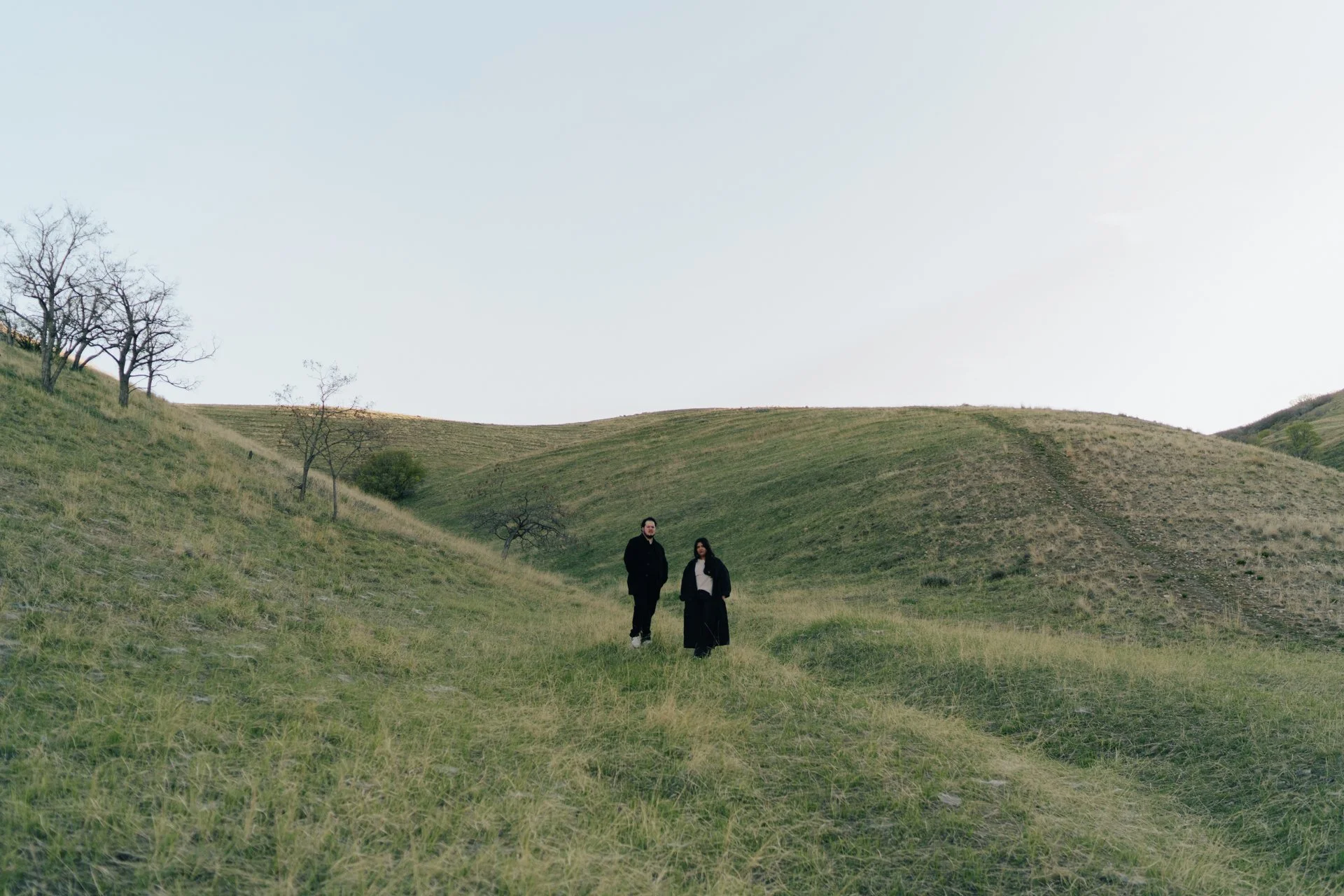 a couple stands together in a softly lit green field together - photographed by poise and ivy imagery