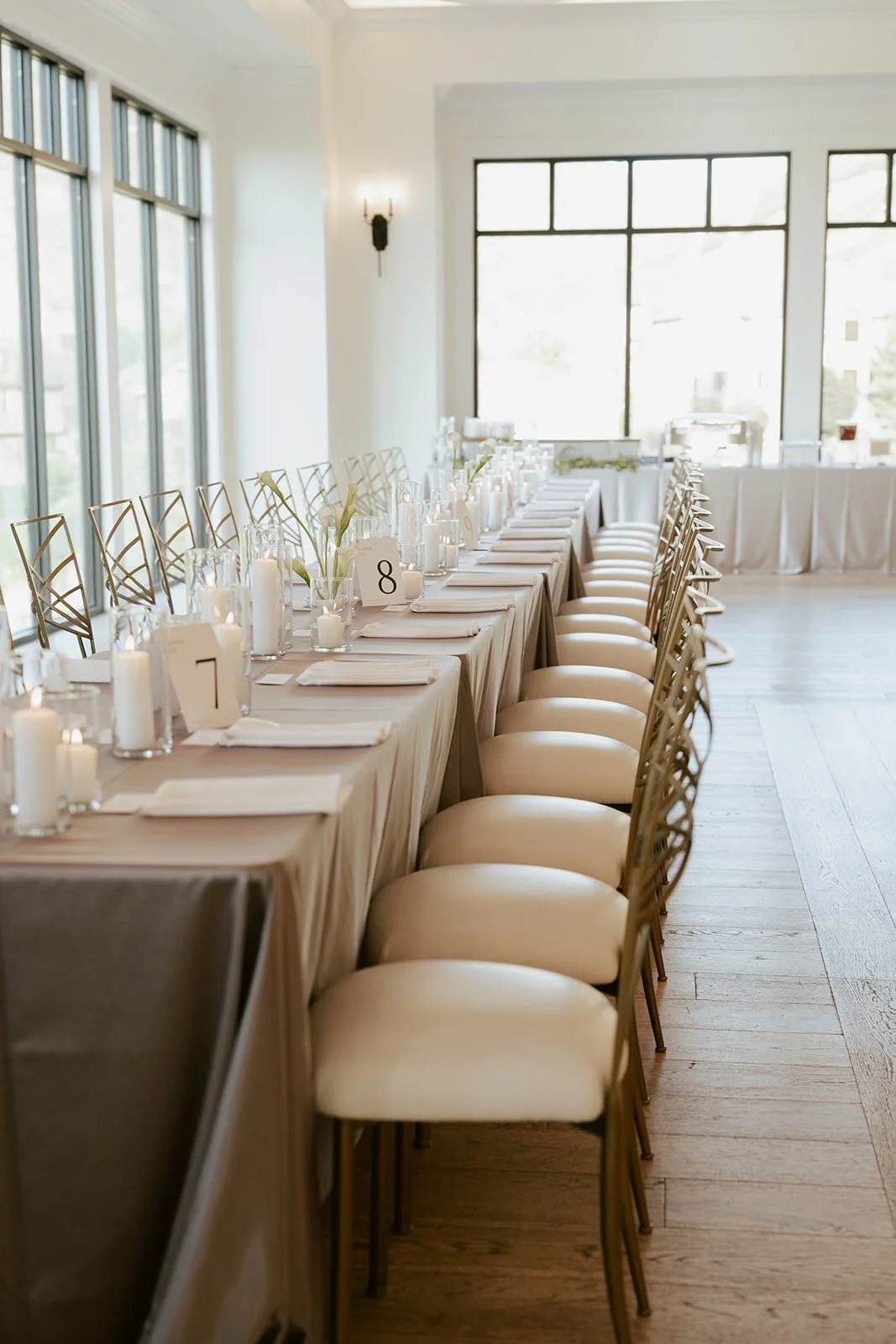wedding reception details featuring white pillar candles in glass vases against a soft grey tablecloth - Photography by Poise and Ivy Imagery, Wedding Design by Britt Warnick Designs