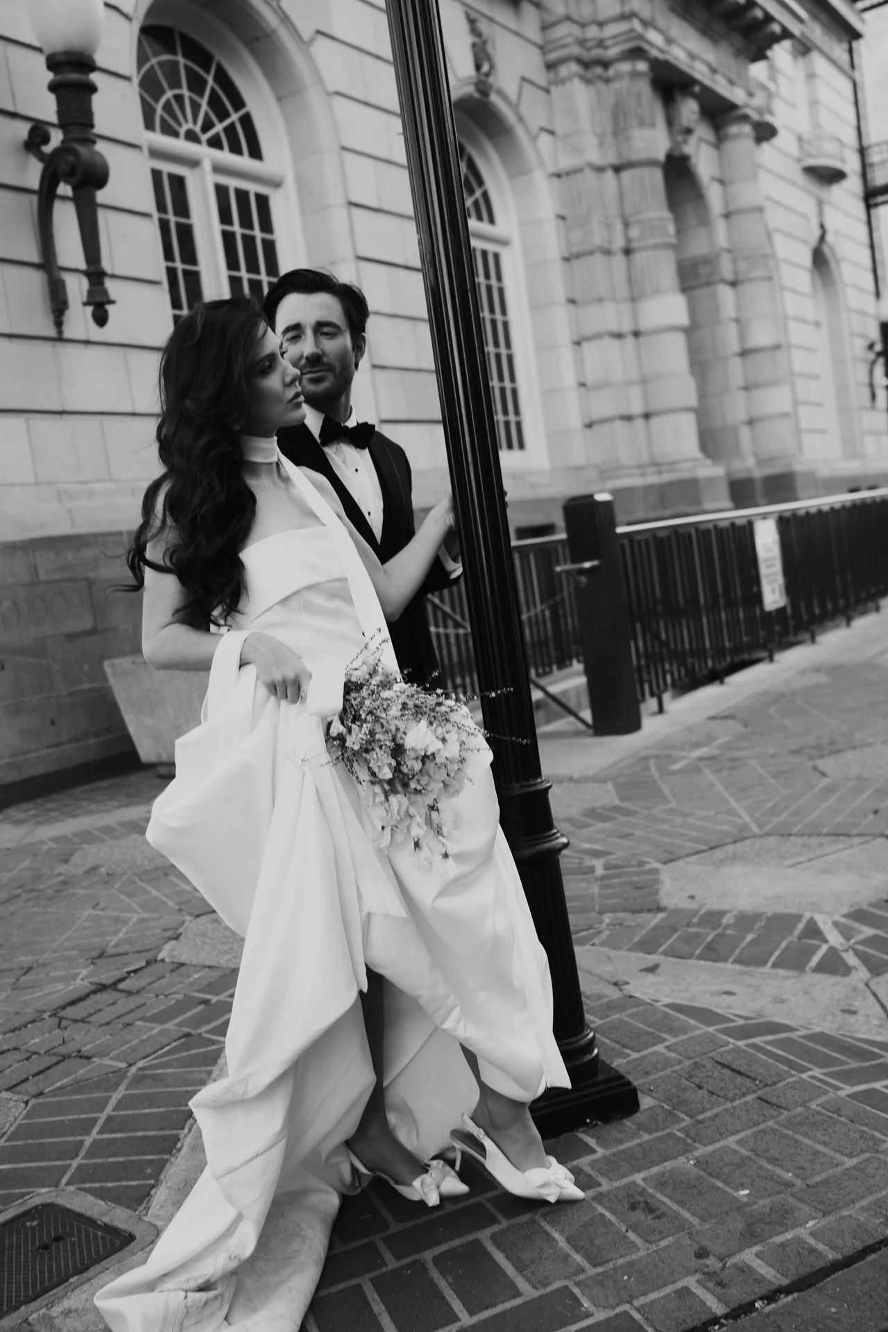 Bride and Groom in classic elegant wedding attire surrounded by beautiful stonework architecture during a downtown formals photoshoot - Poise and Ivy Imagery