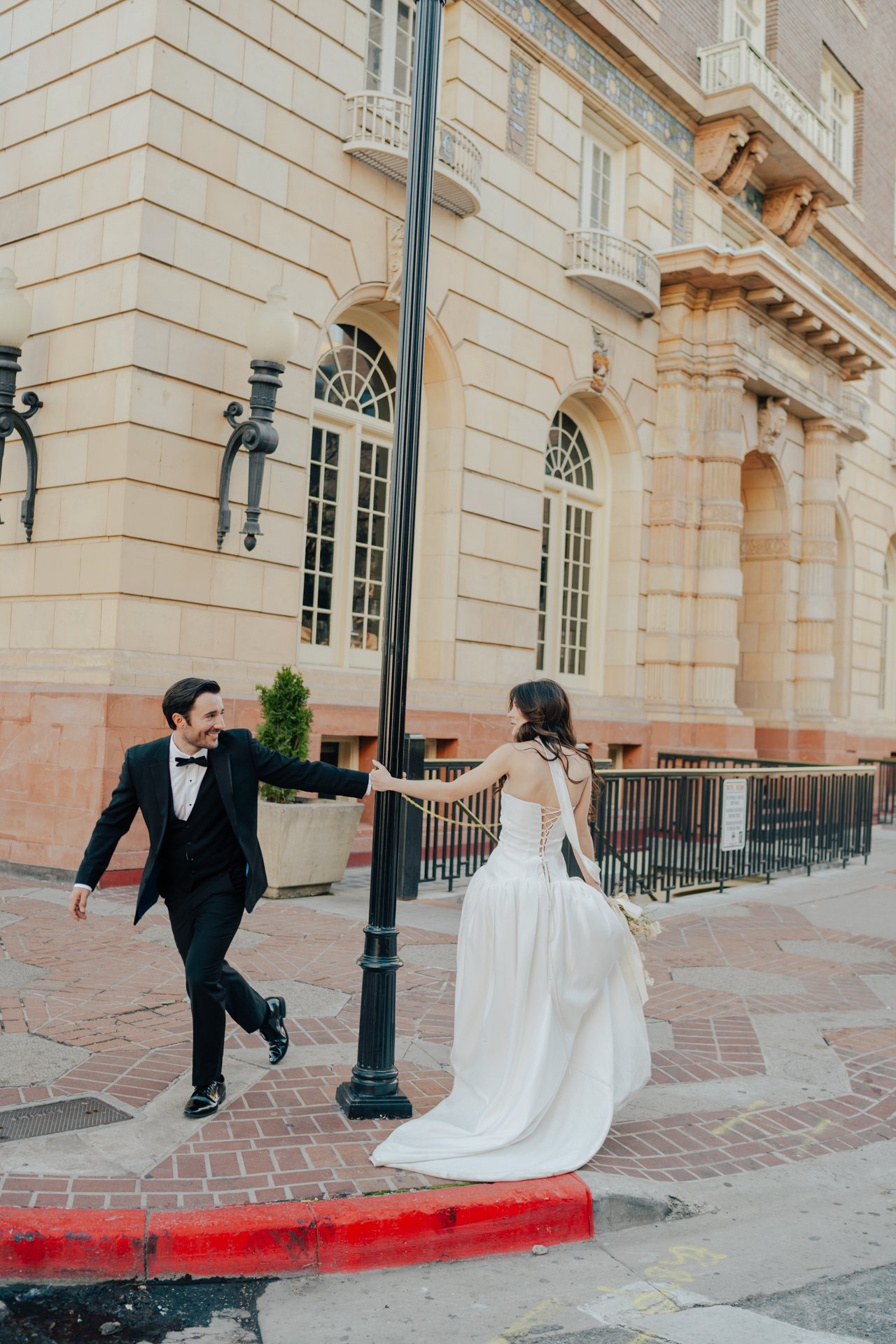 Bride and Groom in classic elegant wedding attire surrounded by beautiful stonework architecture during a downtown formals photoshoot - Poise and Ivy Imagery