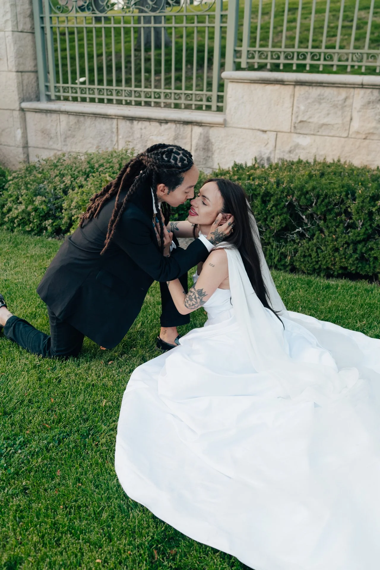 Two brides embrace in front of an ornamental museum of art - poise and ivy imagery