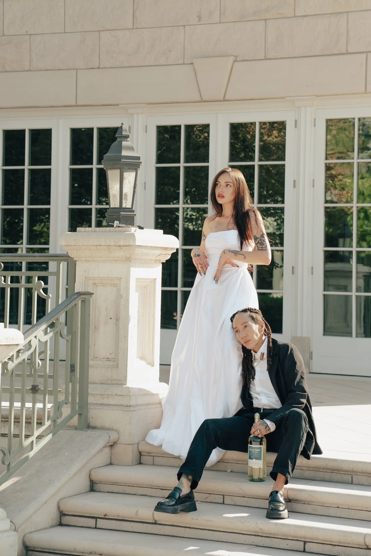 Two brides embrace each other on the ornate steps of an art museum wedding venue - Poise and Ivy ImageryI