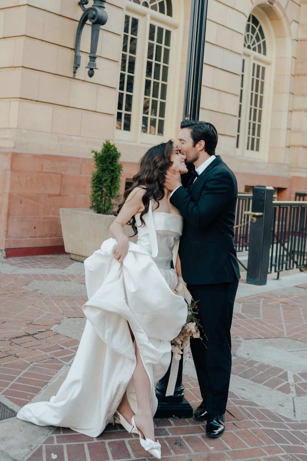 Bride and Groom in classic elegant wedding attire surrounded by beautiful stonework architecture during a downtown formals photoshoot - Poise and Ivy Imagery