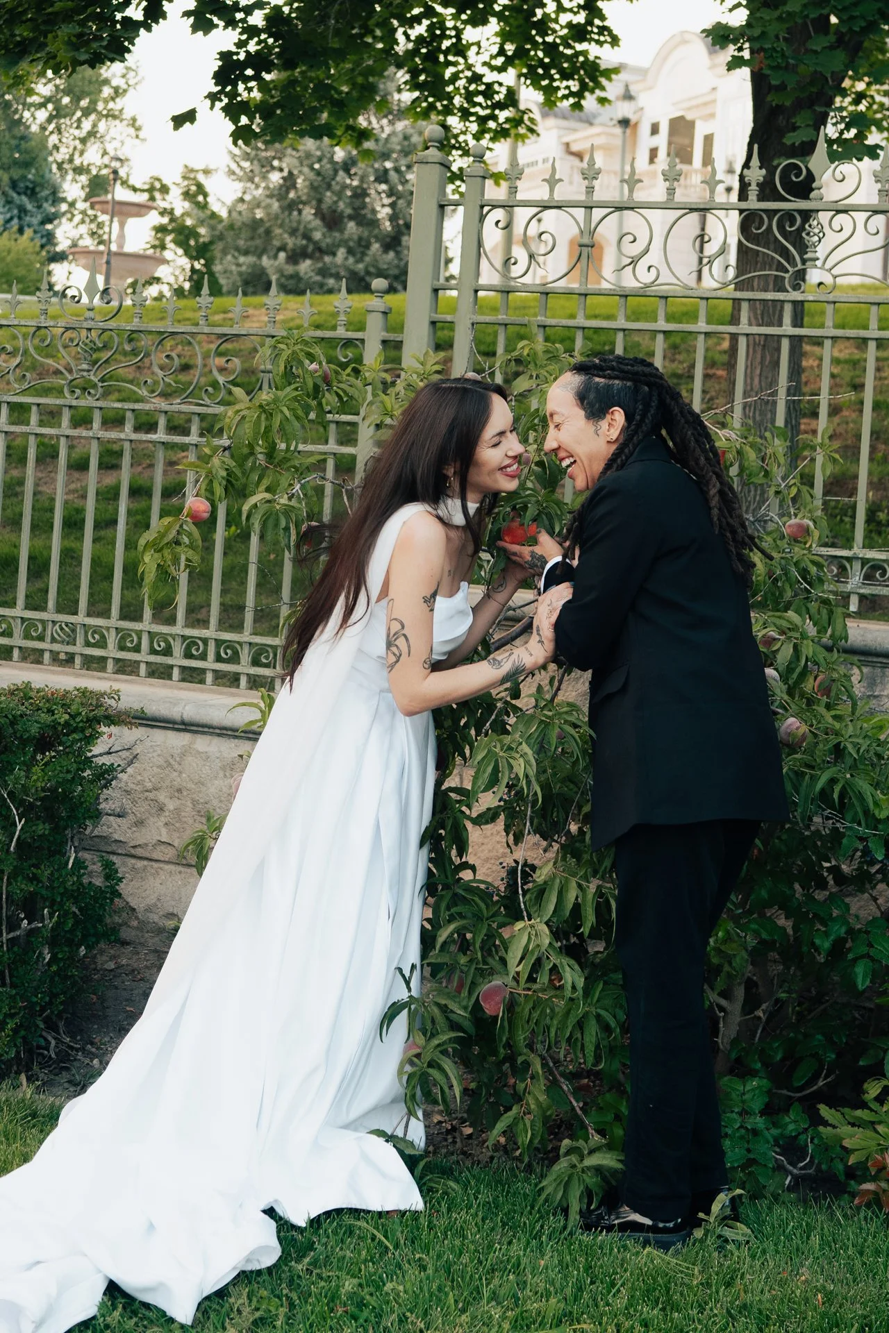 Two brides embrace in front of an ornamental museum of art - poise and ivy imagery