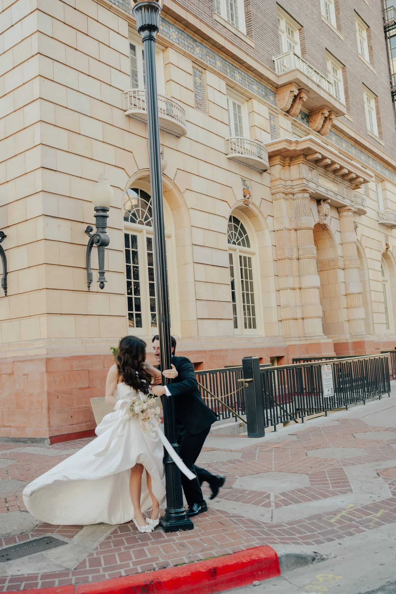 Bride and Groom in classic elegant wedding attire surrounded by beautiful stonework architecture during a downtown formals photoshoot - Poise and Ivy Imagery