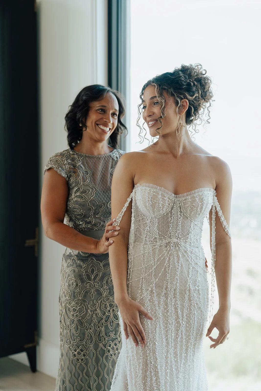 a bride getting ready for her marriage ceremony while her mother helps her into her beaded wedding dress- Photography by Poise and Ivy Imagery