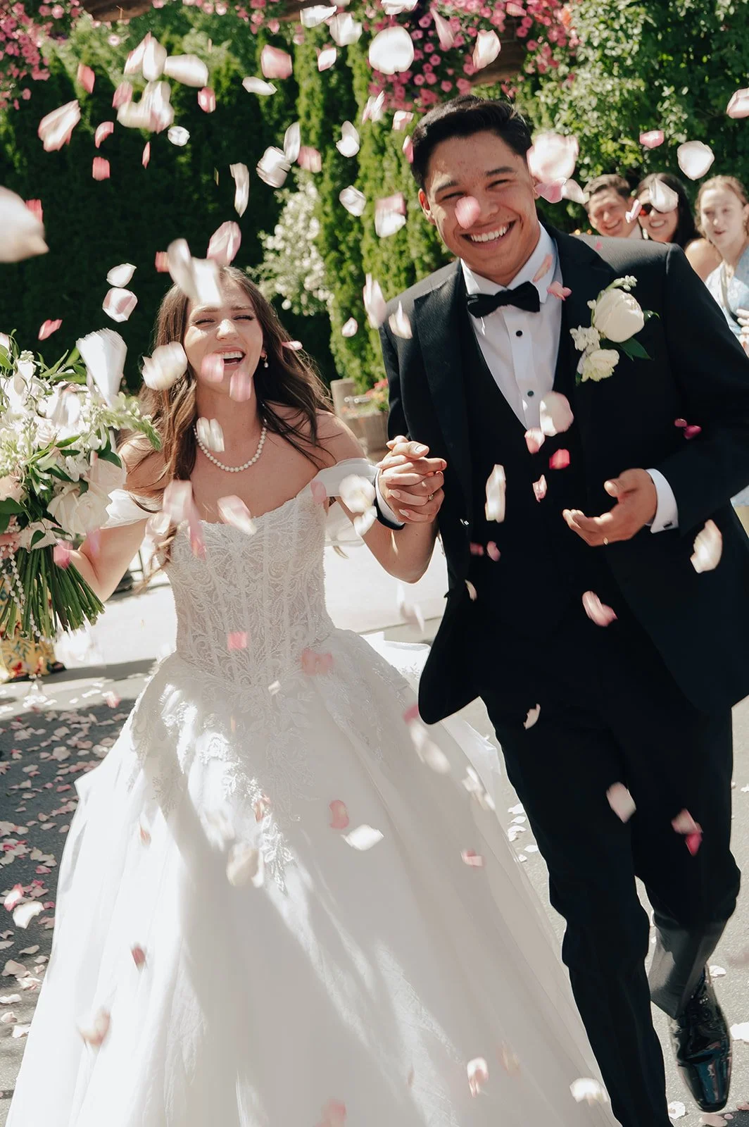 Bride and Groom celebrate their marriage under a petal toss wedding exit from their guests, captured by wedding photographer Poise & Ivy Imagery