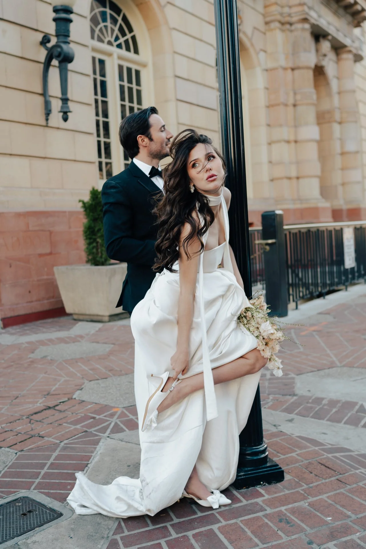 Bride and Groom in classic elegant wedding attire surrounded by beautiful stonework architecture during a downtown formals photoshoot - Poise and Ivy Imagery
