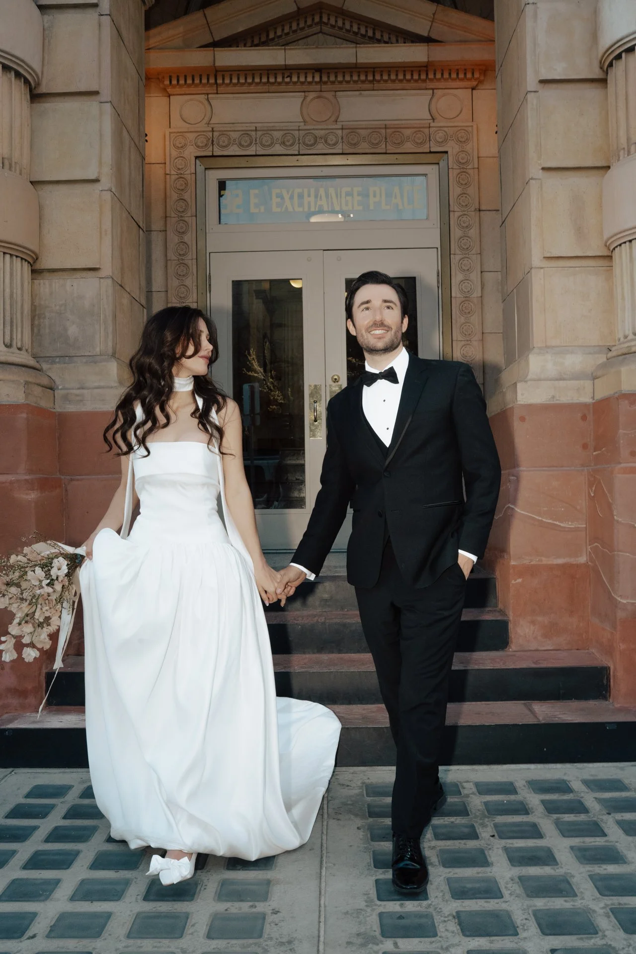 Bride and Groom in classic elegant wedding attire surrounded by beautiful stonework architecture during a downtown formals photoshoot - Poise and Ivy Imagery